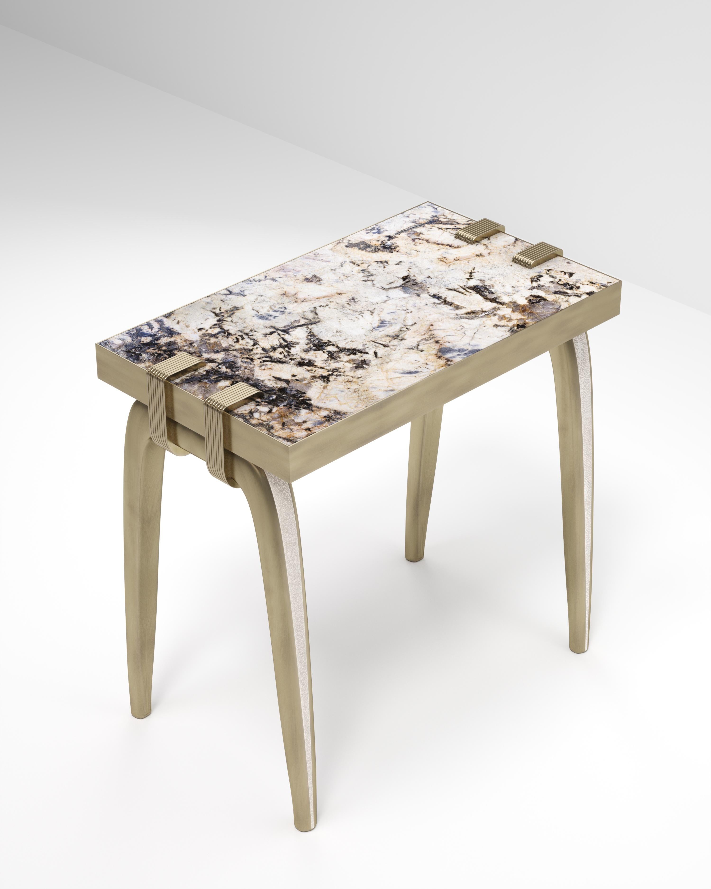 La table d'appoint Sonia est un modèle emblématique d'Augousti, qui met en valeur le savoir-faire exquis de la marque. Les pieds incrustés de galuchat s'accrochent sur le côté du plateau rectangulaire patagonia. Cette pièce est un clin d'œil à la