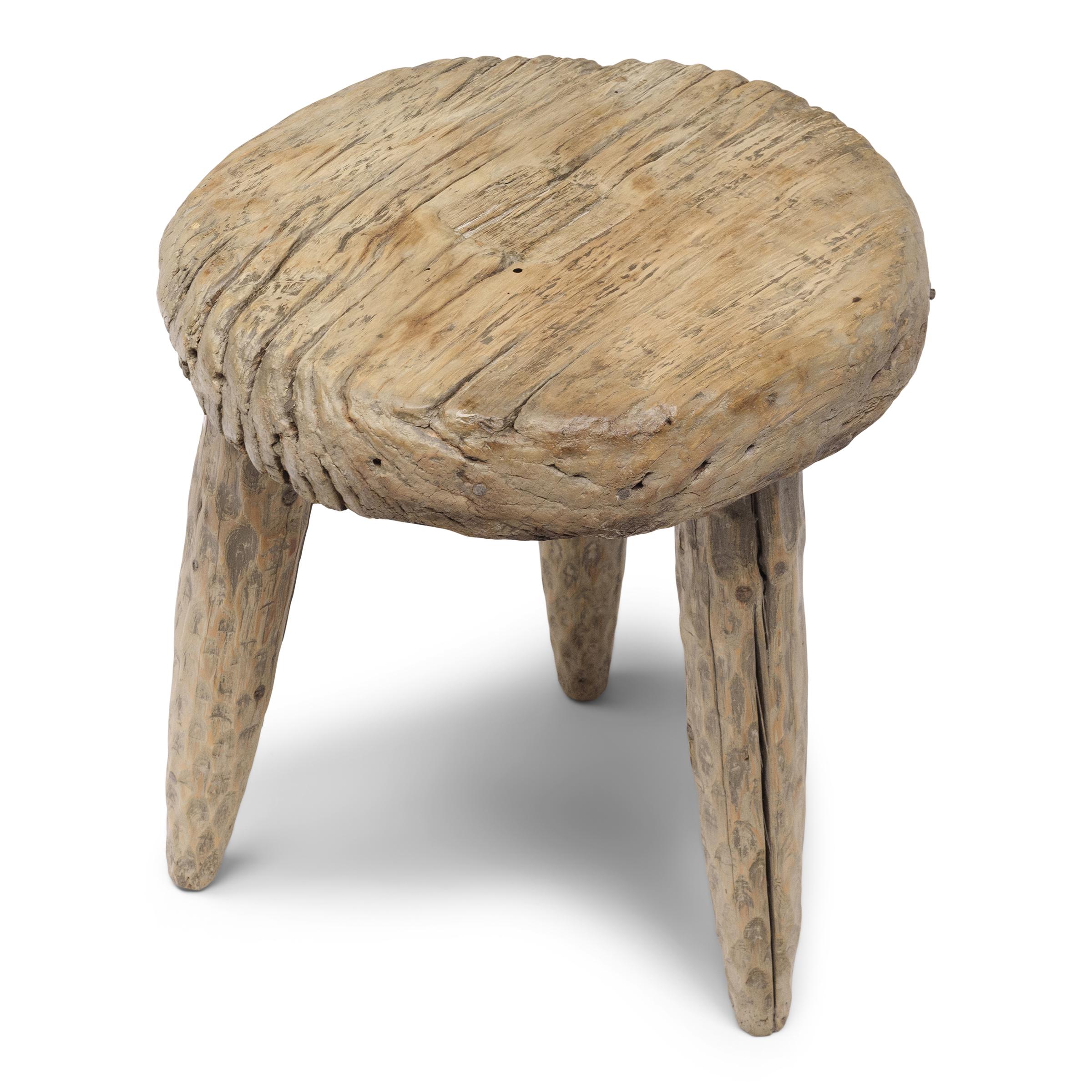Le plateau rond de cette table d'appoint rustique à trois pieds est une roue de charrette antique en bois, provenant d'un chariot tiré par des bœufs ou d'une charrette de ferme du début du XXe siècle. Riche en caractère, la roue est texturée par de