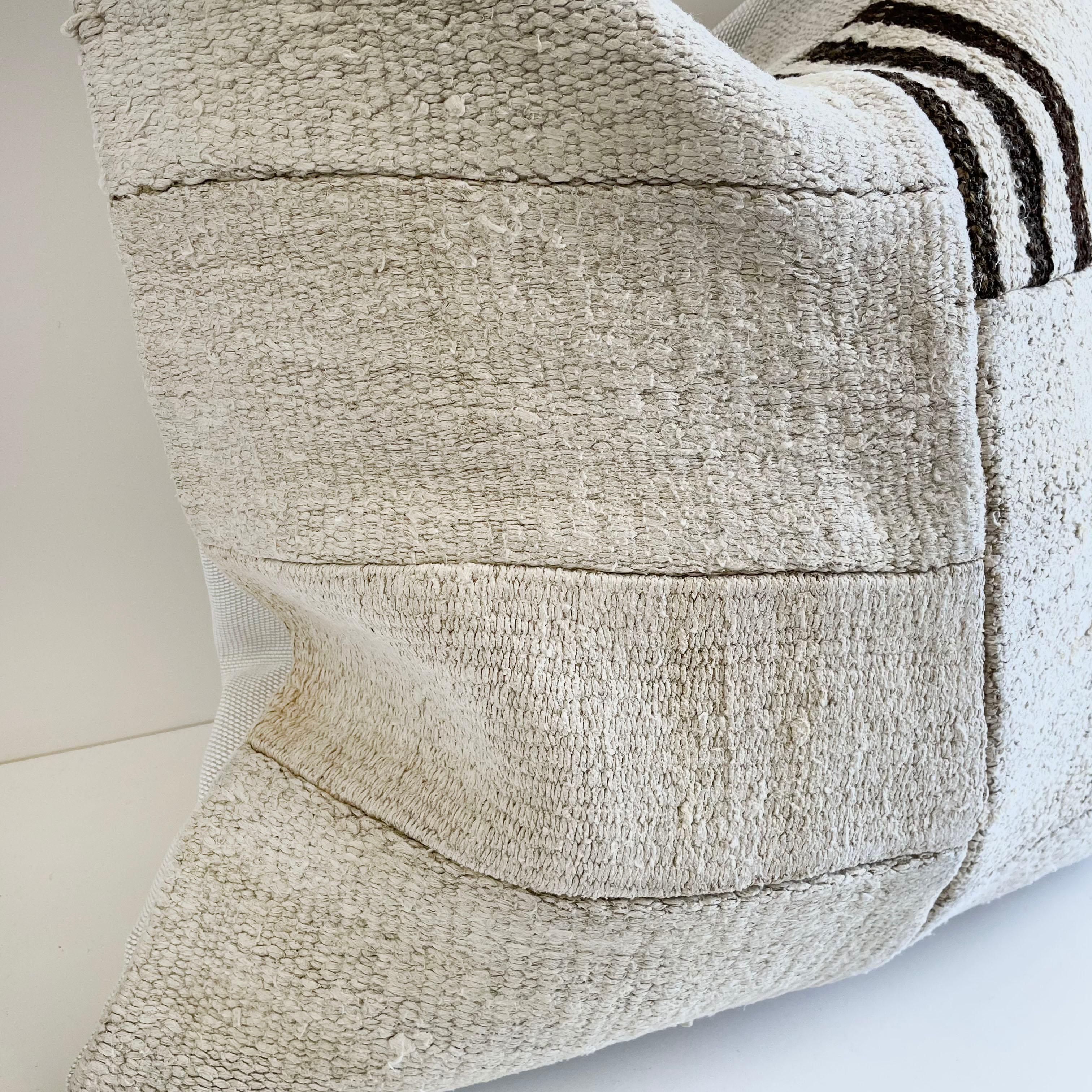 Creamy white hemp rug with brown and natural patchwork style. Unique patchwork pillow has been made with parts of different Turkish rugs, in multiple white tones, and some with stripes. The face is fully lined, with a coordinating backing in a solid