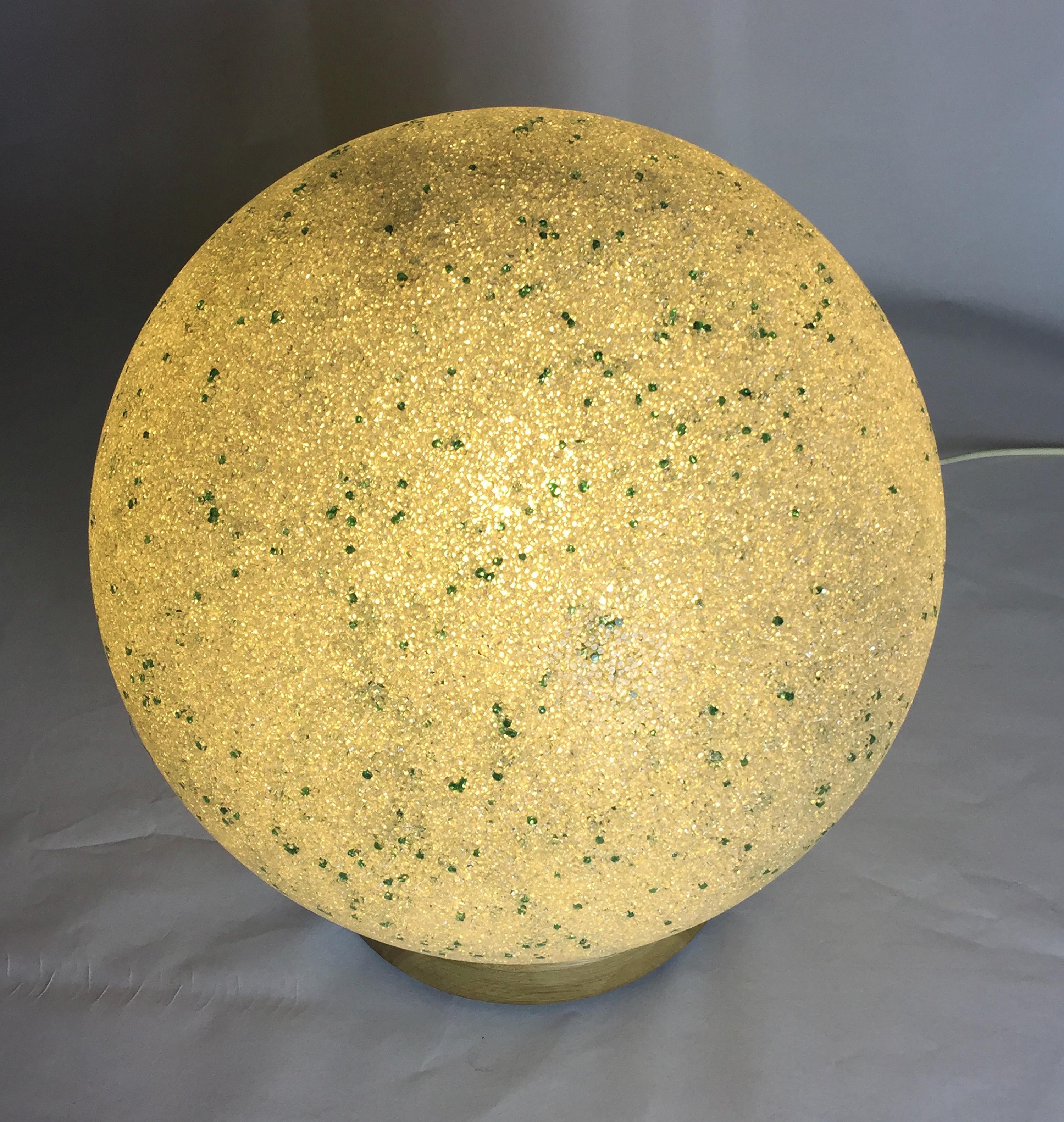 Delicate pâte de verre lamp with green inclusions. Made in Murano in 1960. Originally a pendant light, now mounted on a turned oak base with lamp holder.

The process of making Pate d'Verre is by pushing glass beads into a mould and then fusing