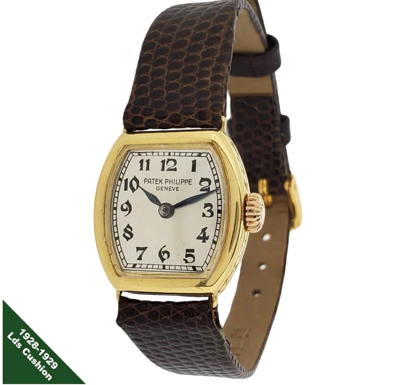 Patek Philippe 1928-1929 Early Cushion Ladies Watch ;  Réalisée en or jaune 18 carats, elle mesure 21 x 21 mm et possède un cadran argenté, des chiffres Breguet noirs et des aiguilles en acier bleu.  La montre est équipée d'un mouvement à remontage