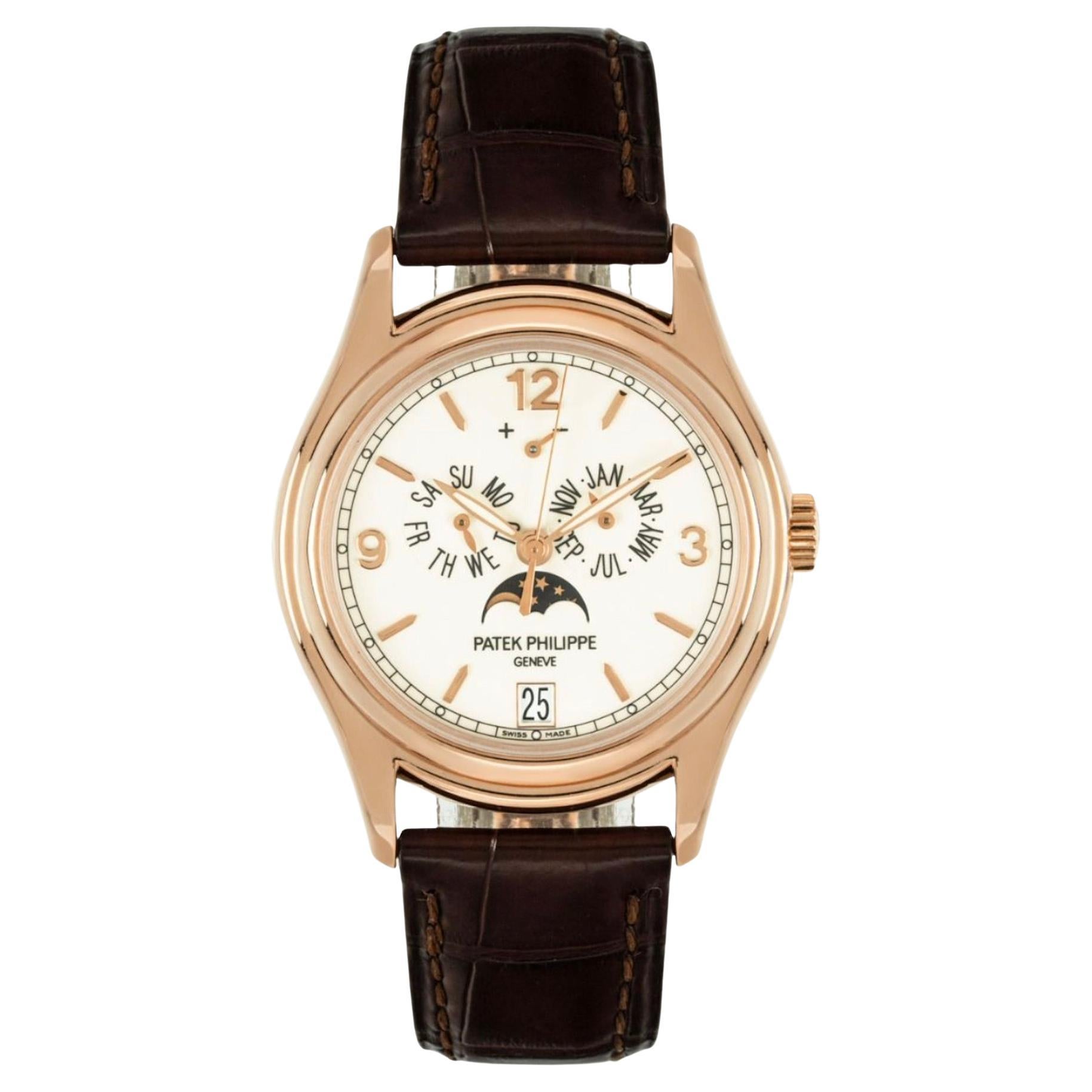 An Annual Calendar crafted in rose gold by Patek Philippe. Featuring a cream dial with displays of the day, date and month. The dial further features a moon phase display and a power reserve indicator.

The watch is presented on an original brown