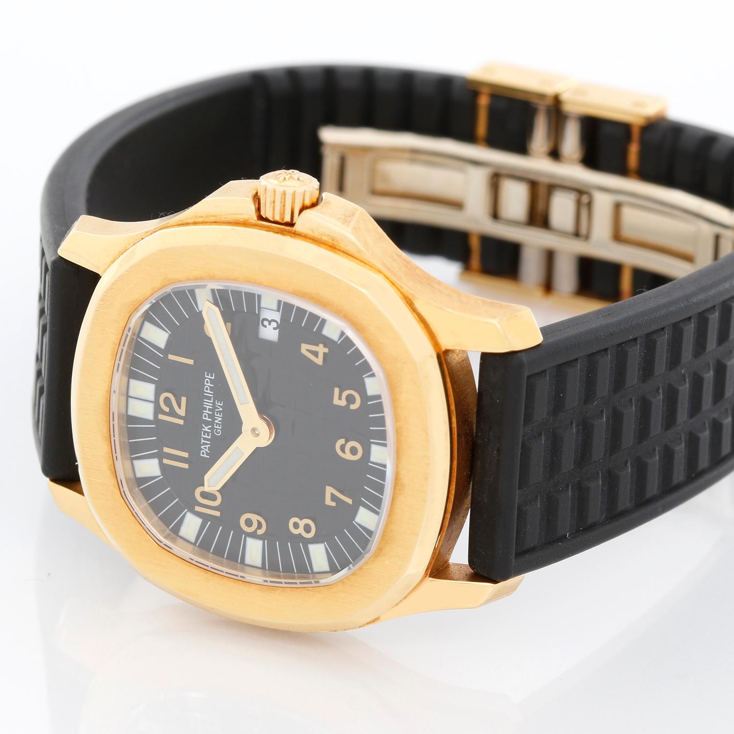 Patek Philippe Aquanaut 18K Yellow Gold Watch 4960 J - Quartz. 18K Yellow gold ( 30 mm ). Black dial with Arabic numerals. Black rubber strap  band with 18k yellow gold Patek Philippe deployant clasp. Pre-owned with Patek Philippe box and books.