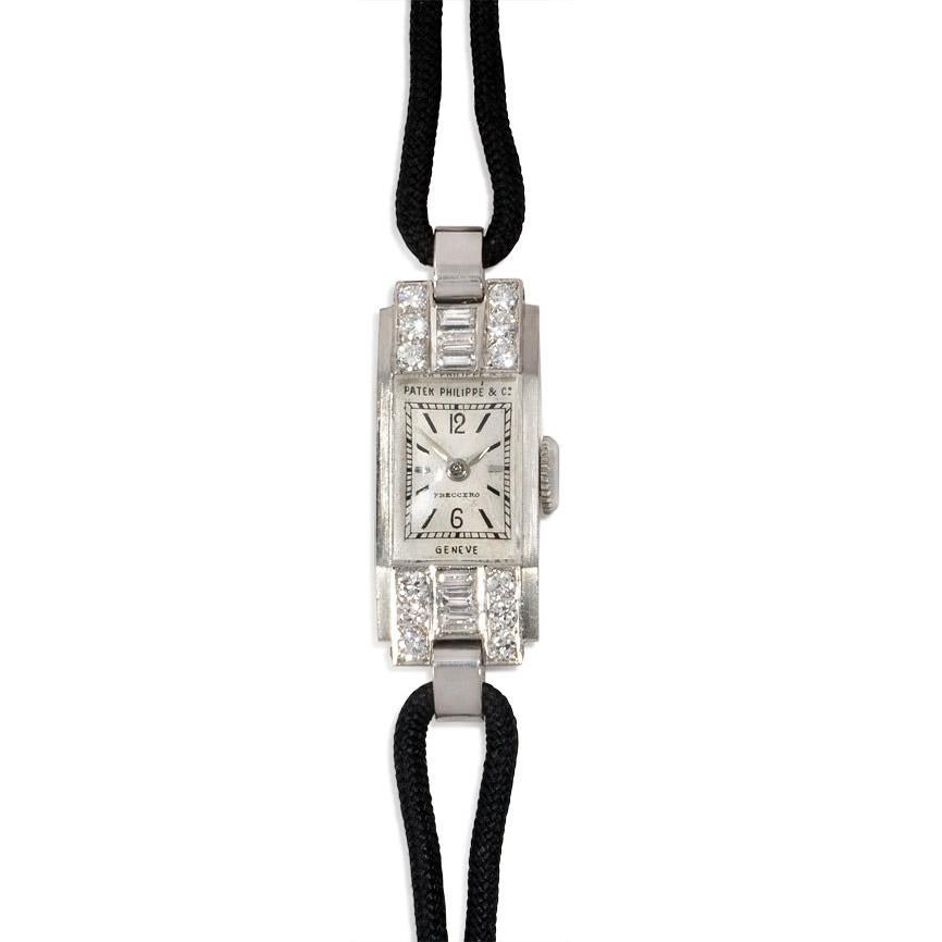 An Art Deco diamond dress watch of stepped design with a rectangular face, set with round, baguette, and rose-cut diamonds, in platinum. Patek Philippe, Geneva.  Atw. 0.80 ct. diamonds

Watch face dimensions: 37 x 14 mm