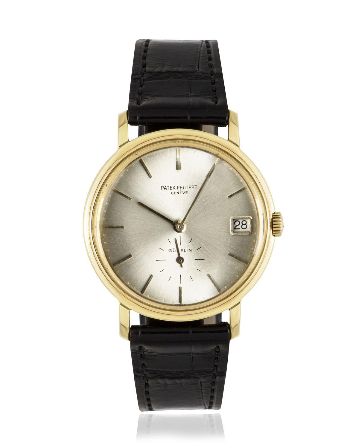 A vintage 35 mm yellow gold Calatrava by Patek Philippe. Features a double name Gubelin signed silver dial with a date and small seconds display. An original black leather strap comes with an original yellow gold pin buckle. Fitted with plastic