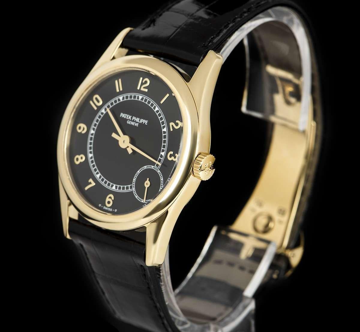 An 18k Yellow Gold Calatrava Gents Wristwatch, black dial with applied arabic numbers, small seconds between 4 and 5 0'clock, a fixed 18k yellow gold bezel, a brand new original black leather strap with an original 18k yellow gold deployant clasp,