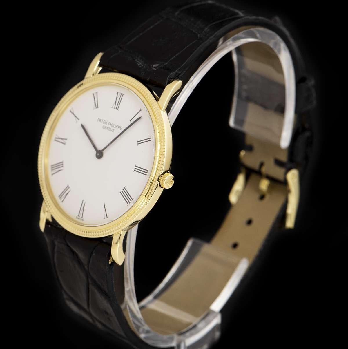 An 18k Yellow Gold Calatrava Gents Wristwatch, white dial with roman numerals, a fixed 18k yellow gold hobnail patterned bezel, an original black leather strap with an original 18k yellow gold pin buckle, sapphire glass, manual wind movement, in