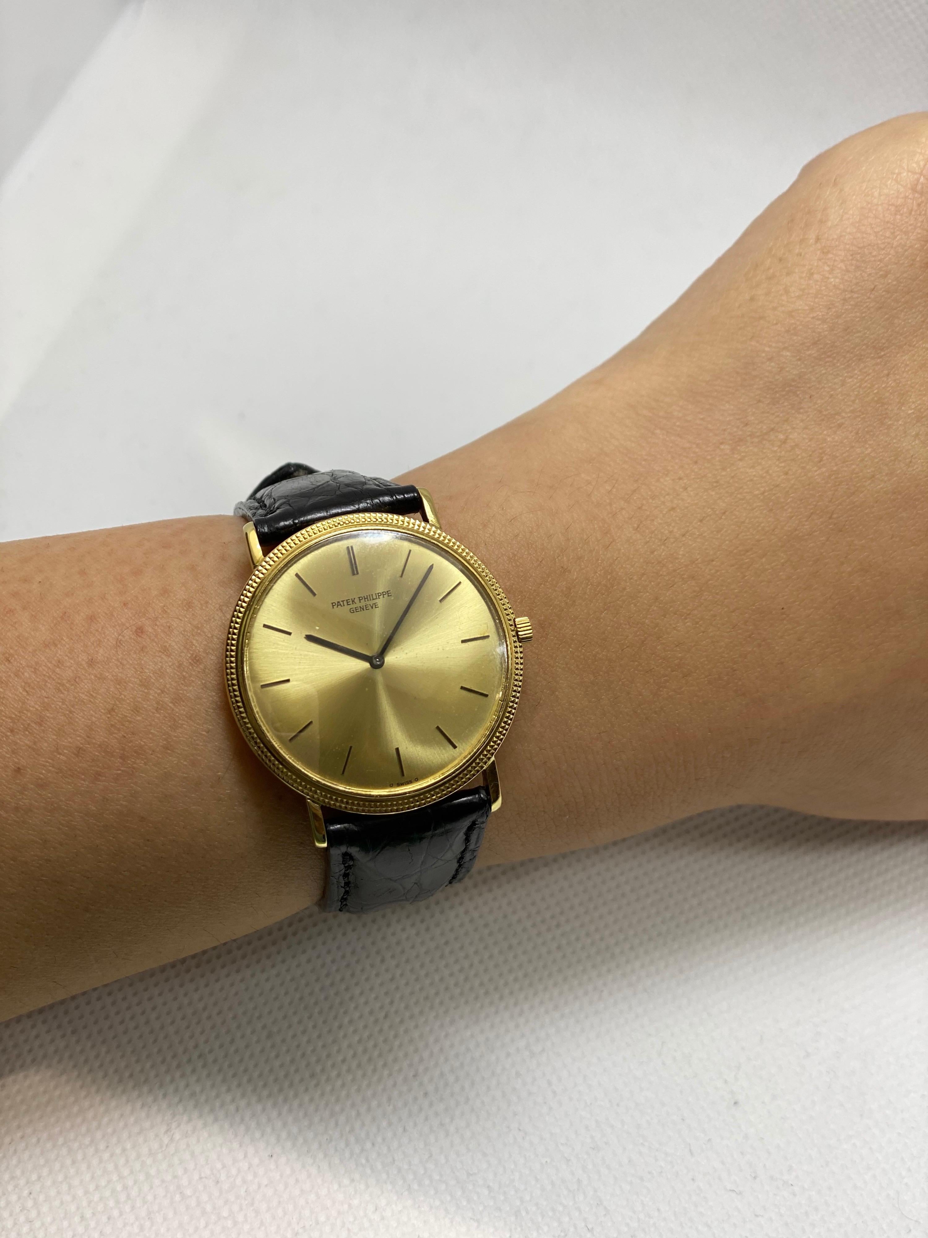 A 32 mm 1970s 18k Yellow Gold Calatrava Vintage Men's Wristwatch, champagne dial with applied hour markers, a fixed 18k yellow gold bezel, a black leather strap with a gold plated pin buckle (both not by Patek Philippe), mineral glass, manual wind