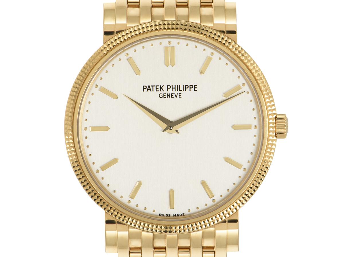 A 35 mm yellow gold Calatrava by Patek Philippe, featuring a silvered dial and hobnail bezel. The bracelet is bound together by a jewellery style clasp. Fitted with sapphire crystal and a calibre 240 self-winding automatic movement showcased by the
