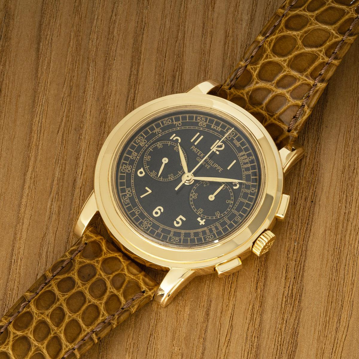 A Complications Chronograph in yellow gold by Patek Philippe. Featuring a black dial with Arabic numbers , a tachymeter scale, and two sub-dials; a 30 minute recorder and small seconds. Complementing the piece is a smooth yellow gold bezel.

Fitted