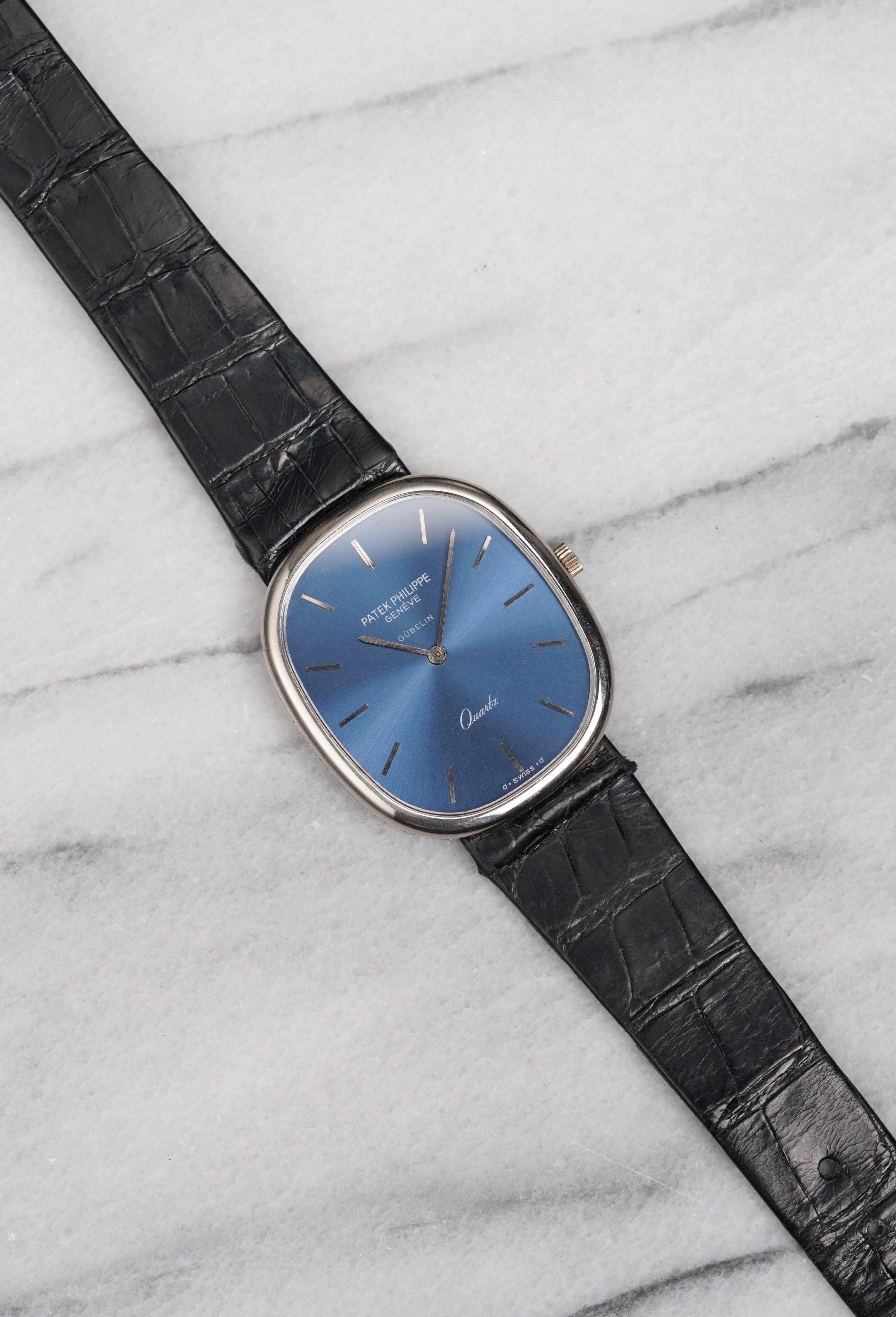 Aquí tienes una Patek Philippe Ellipse de cuarzo de oro blanco de 18 quilates con esfera azul soleada firmada por Gubelin, el prestigioso minorista suizo de los años 80. Las medidas incluyen una caja de 34 mm. Con su correa original de piel de