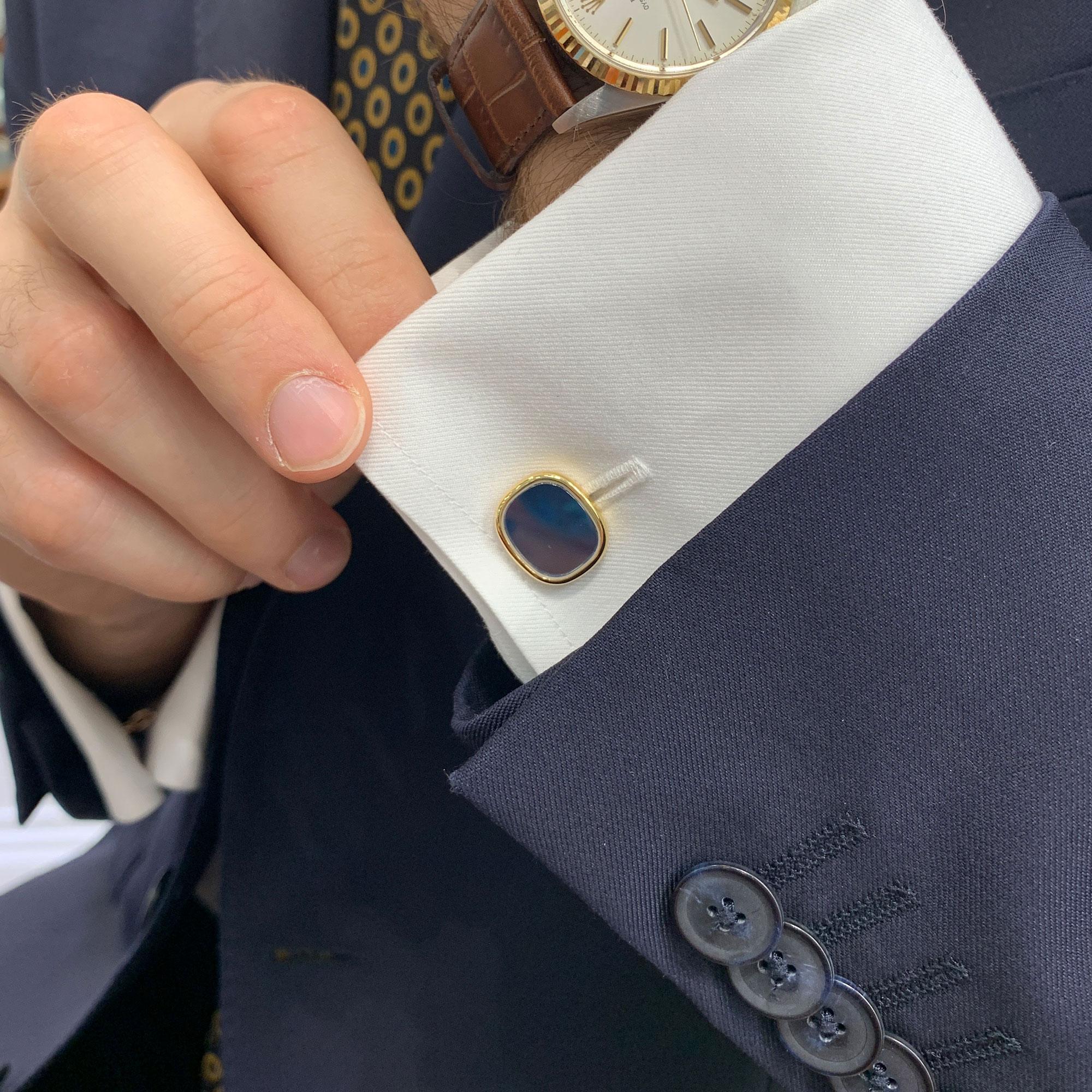 A classic pair of Patek Philippe cufflinks set in 18 carat yellow gold. 

Each cufflink is composed of a cushion-shape plaque decorated with grayish-blue guilloche enamel depicting a radial pattern. This is then capped with a rock crystal tablet,