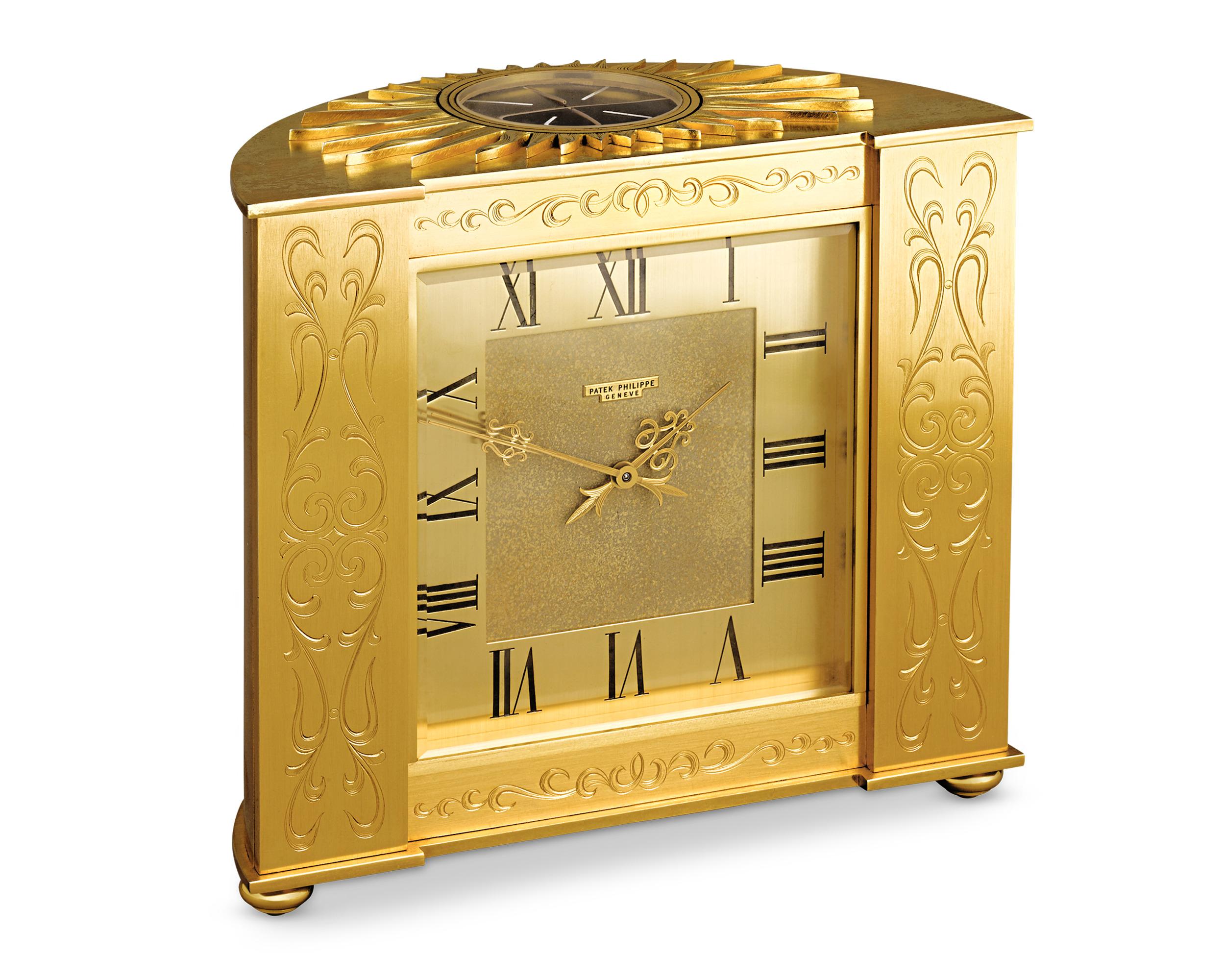 This rare 1961 solar clock by Patek Philippe has an Empire-inspired aesthetic, exuding timeless luxury. Featuring a demi-lune shaped case and ornate engraved designs, this gilded brass clock is topped with a hand-carved sun motif surrounding its