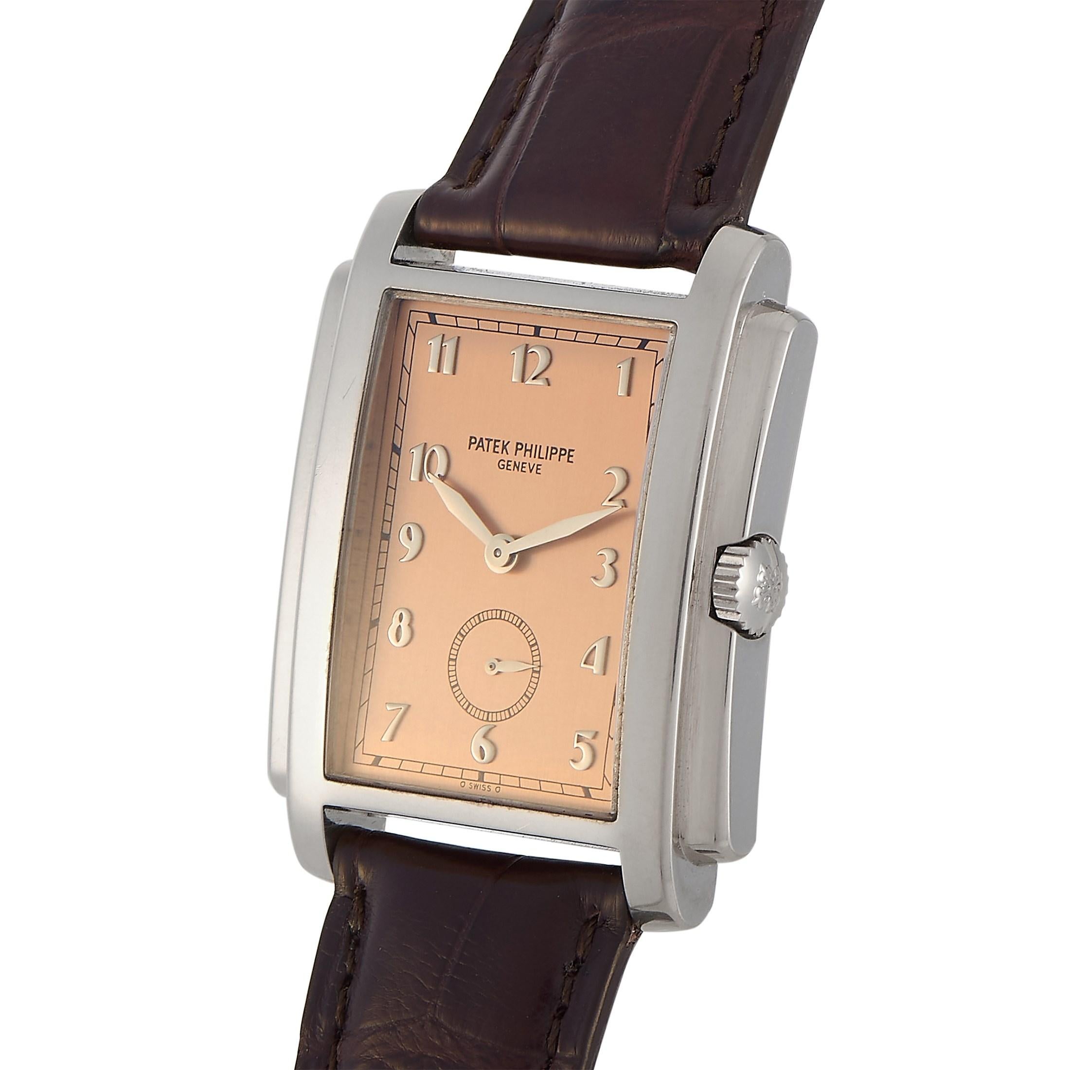 The elegant Gondolo 5024G-001 watch from Patek Philippe displays an 18K white gold rectangular Art Deco-inspired case with stepped sides. It is paired with a salmon pink dial with white gold hands and Roman Numeral hour markers. An alligator leather