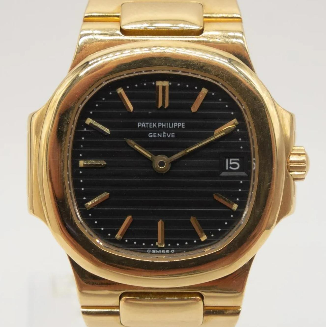 Vintage 1980s Patek Philippe Ladies Wristwatch, Nautilus 4700 in 18k yellow gold. Features a black ridged dial with the date at 3 o'clock and an 18K yellow gold bracelet.  Stamped Patek-Philippe Geneve Nautilus 750 

Case measures 27mm x 29mm,