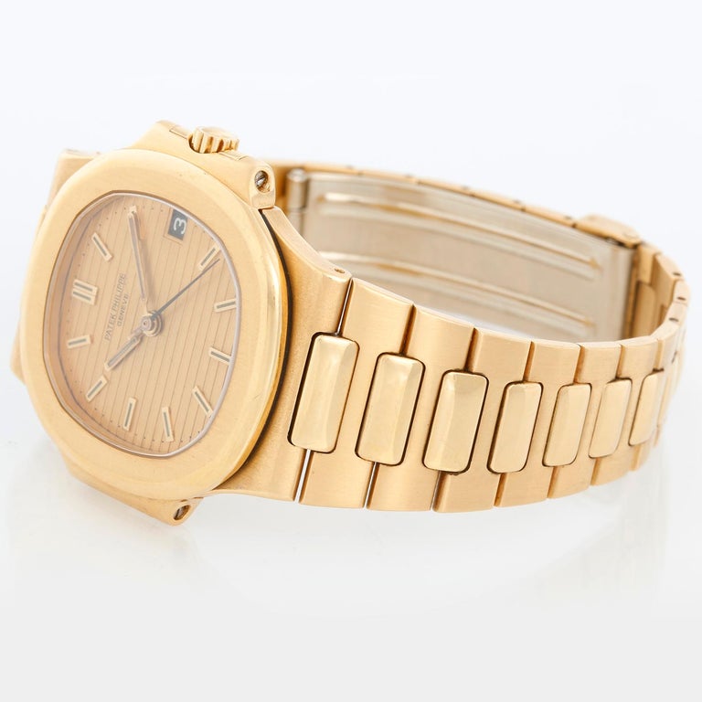 Patek Philippe Nautilus 18k Yellow Gold Watch 3800  J - Automatic winding with date. 18k yellow gold case (37mm). Champagne waffle dial with gold stick hour markers; date at 3 o'clock position. 18k yellow gold Nautilus bracelet with deployant clasp.