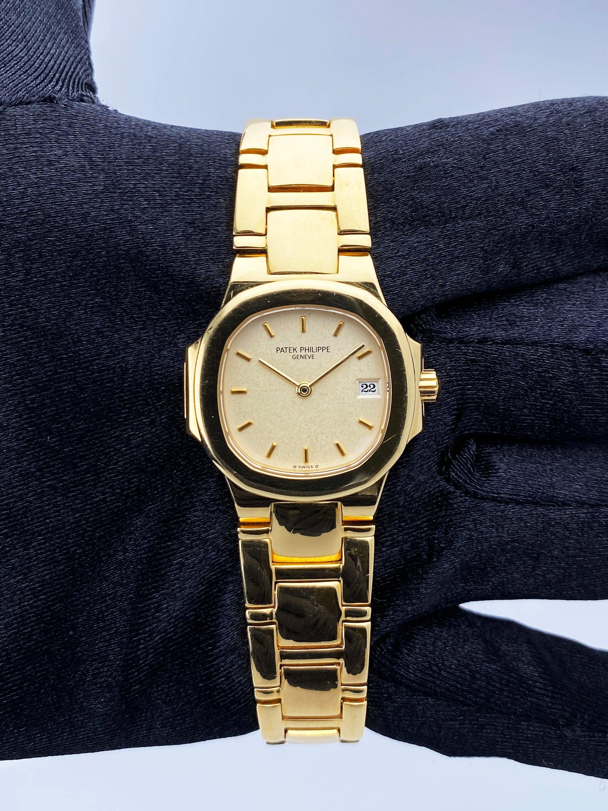 Patek Philippe Nautilus 4700 Ladies Watch. 27mm 18K yellow gold case with 18K yellow gold smooth bezel. Cream dial with gold hands and index hour marker. Date display at 3 o'clock position. 18K yellow gold bracelet with fold over clasp with safety.