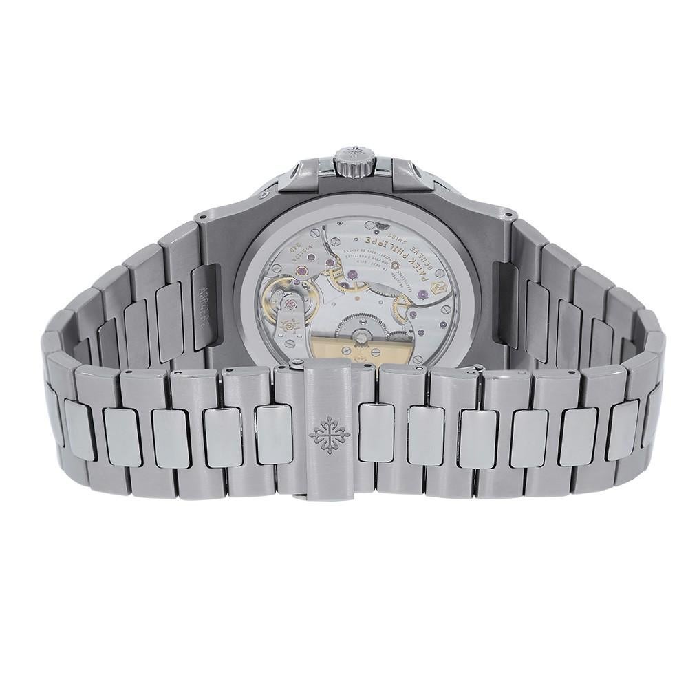 Patek Philippe Nautilus Reference #:5712-1A. Stainless steel case with a stainless steel bracelet. Fixed bezel. Blue dial. Date at 7 o'clock position. Date, moon-phase, small second, power reserve. Automatic movement. Scratch resistant scratch