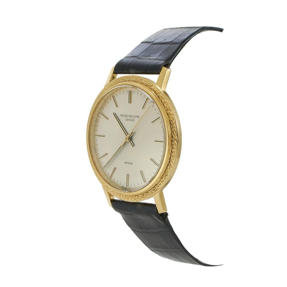 A rare and refined vintage Patek Philippe Calatrava from 1970, featuring the distinctive back-wind design and a coveted double-signed dial. The 36mm 18KT yellow gold case is enhanced by a finely textured bezel, giving the watch a subtle, tactile