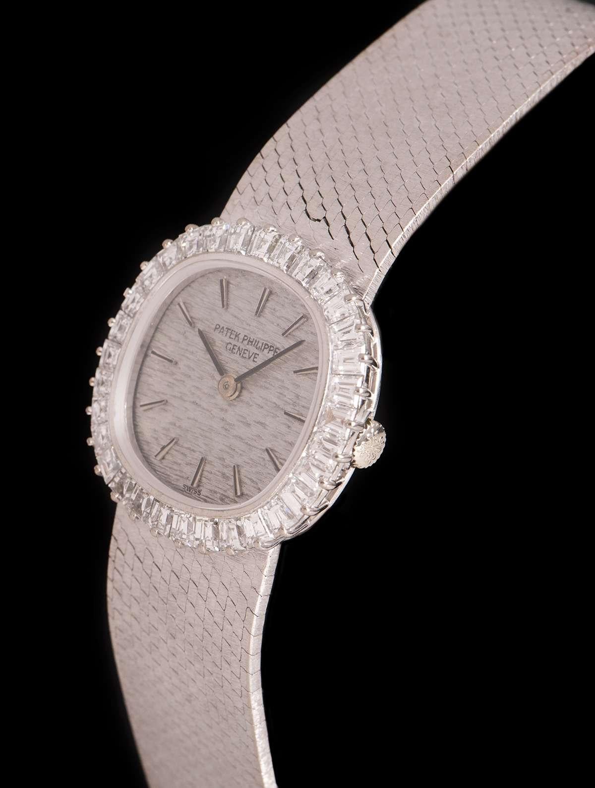 An 18k White Gold Cocktail Ladies Wristwatch, silver dial with applied hour markers, a fixed 18k white gold bezel set with approximately 32 baguette cut diamonds, an 18k white gold integrated bracelet with an 18k white gold jewellery style clasp,