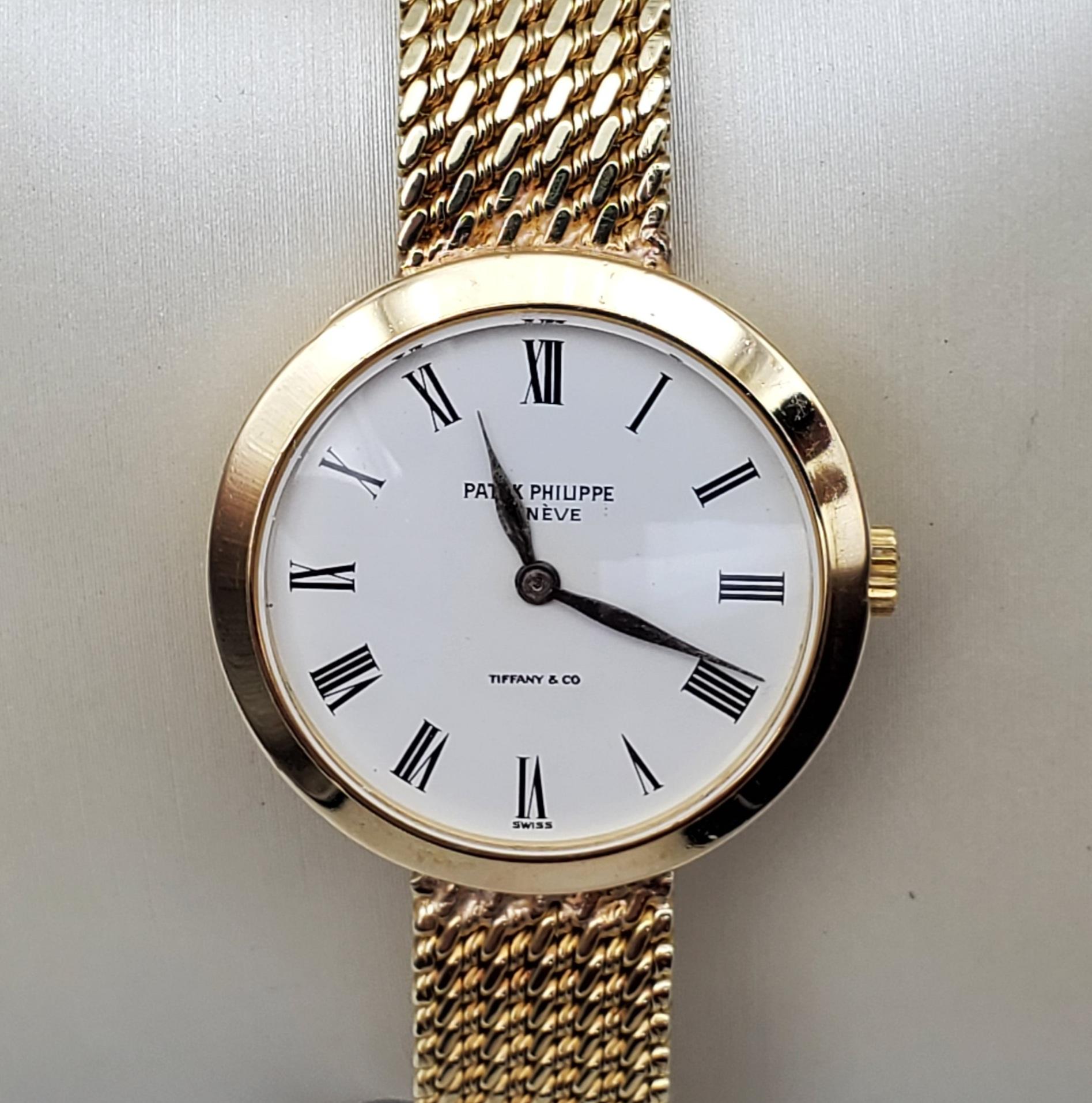 Patek Philippe Tiffany and Co ladies 24mm (6.4mm thick) case watch. Model Calatrava. Off white face with Roman Numerals. The case is 18kt yellow gold and the bracelet is 14kt yellow and was modified. Total weights is 37.6 gams. The buckle is stamped