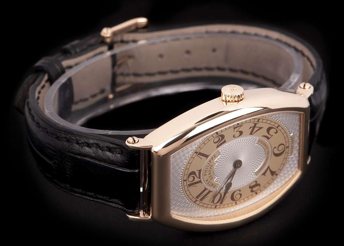 An 18k Rose Gold Tonneau Shaped Gondolo Gents Wristwatch, silver guilloche dial with arabic numbers, a fixed 18k rose gold bezel, an original black leather strap with an original 18k rose gold pin buckle, sapphire glass, exhibition caseback, manual