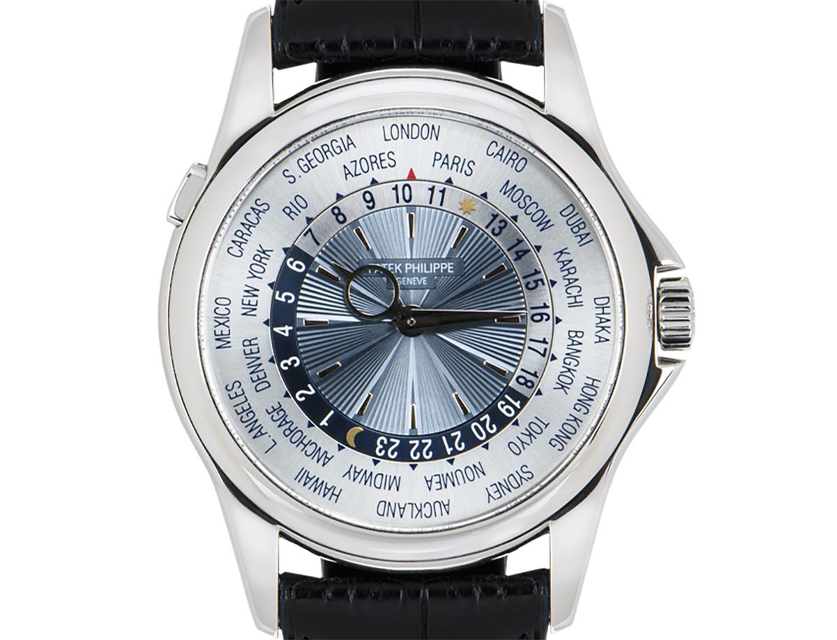 A 39.5 mm World Time in platinum by Patek Philippe. Featuring a silvered sunburst dial with a blue guilloche centre. The dial itself features a 24-hour display and the time of 24 worldwide locations. A black leather strap comes with a platinum