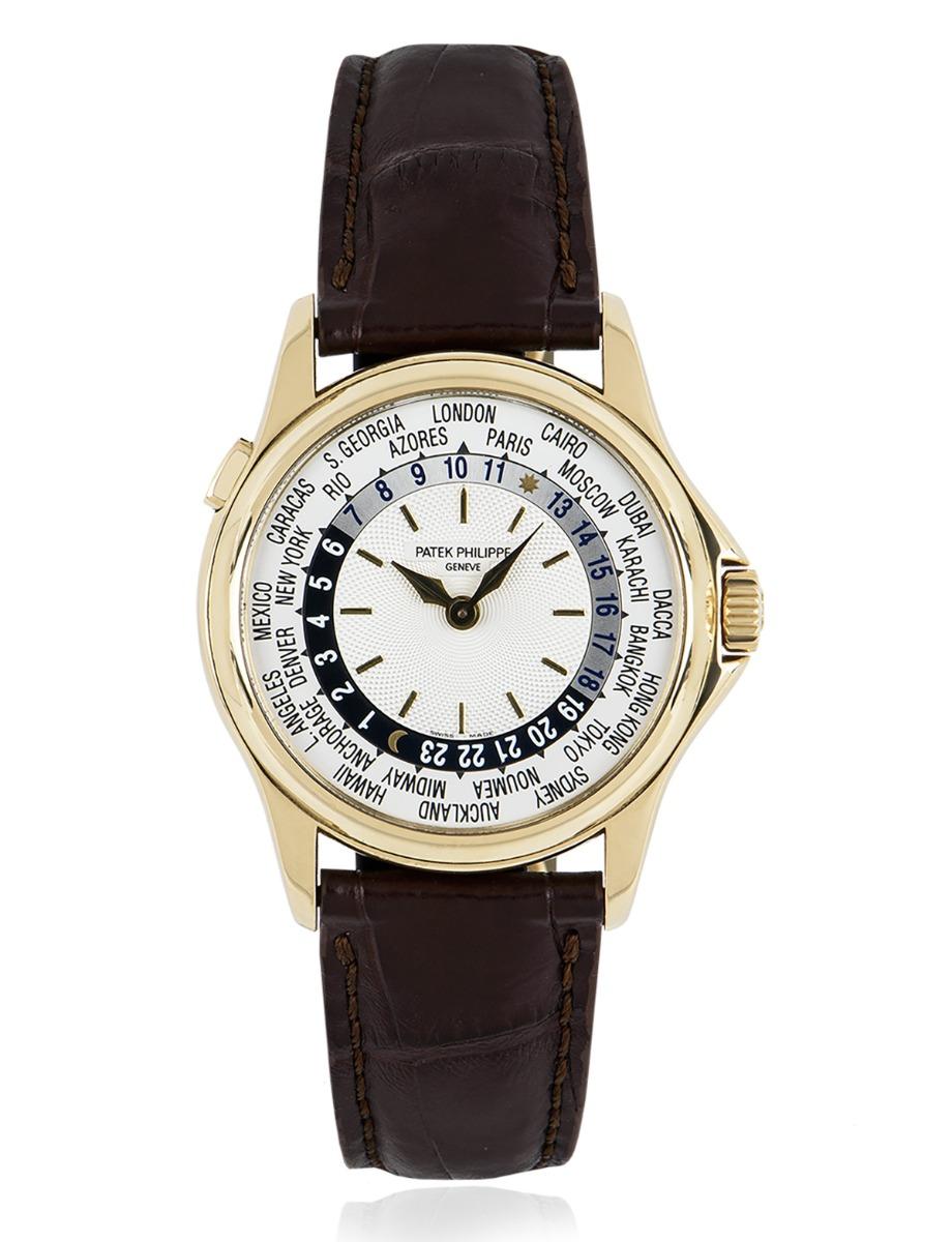 A yellow gold World Time by Patek Philippe. Featuring a silver opaline dial with a 24-hour display and the time of 24 worldwide locations. An original brown leather strap comes with an original yellow gold deployant clasp. Fitted with sapphire