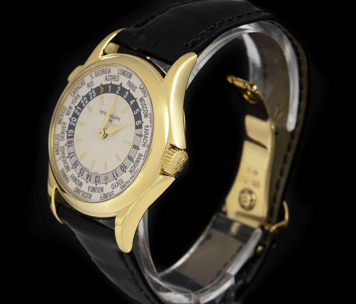 An 18k Yellow Gold World Time Gents Wristwatch, silver dial with applied hour markers, 24 hour indicator with day/night display, 24 time zones on the outer edge of the dial, a fixed 18k yellow gold bezel, a brand new original brown leather strap