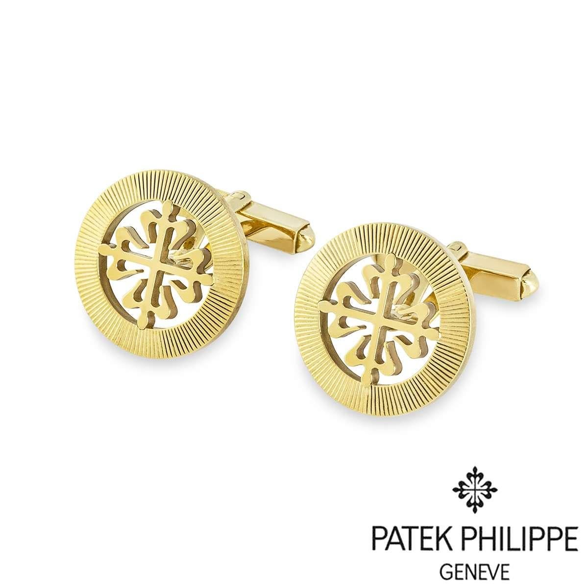 A pair of 18k yellow gold Calatrava cufflinks by Patek Philippe. The cufflinks feature the classic Calatrava cross motif, surrounded by a guilloche outer edge ring. The cufflinks have t-bar fittings and the motif measures 18mm in diameter. The