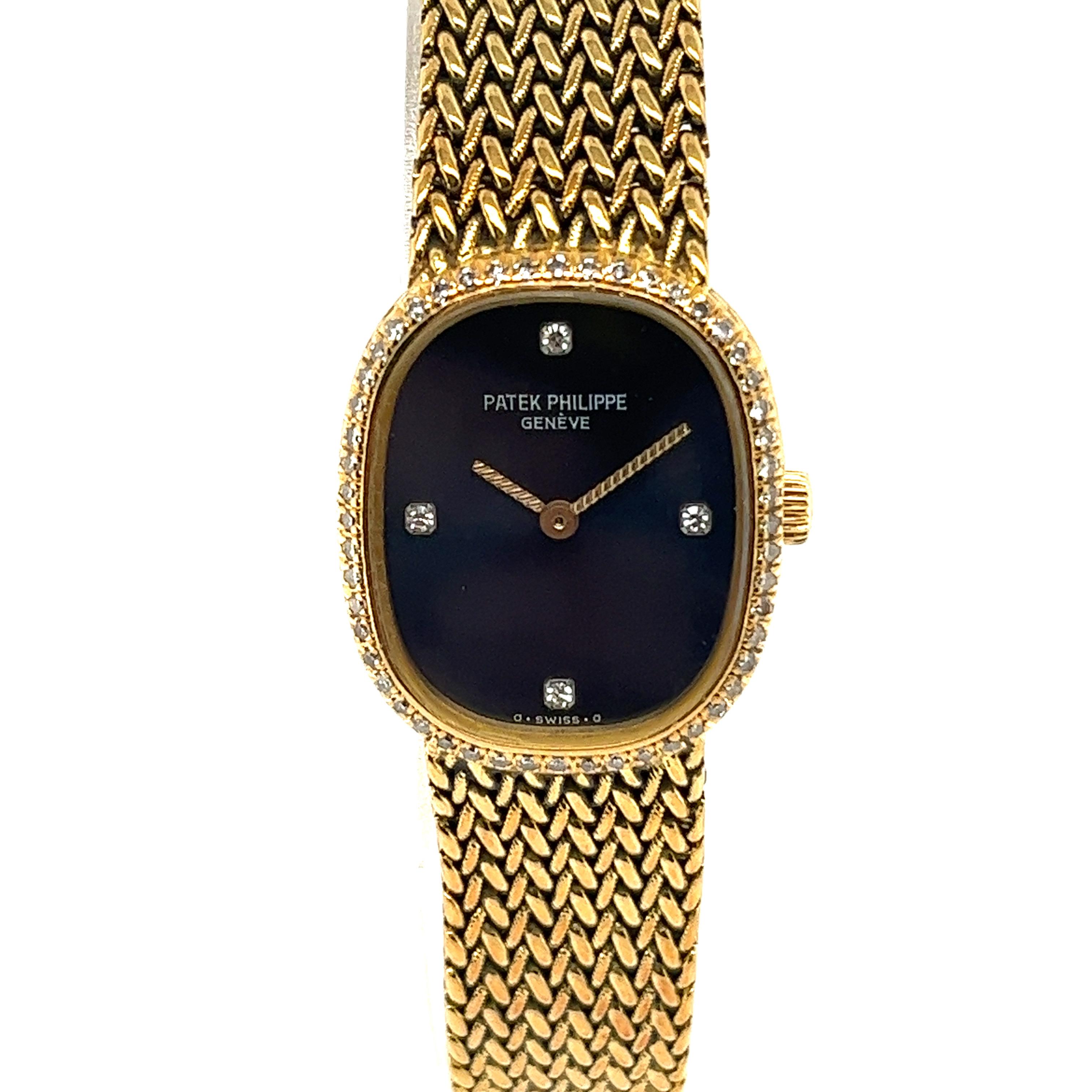 Ladies 18k yellow gold Patek Phillips Ellipse 4498. This stunning pre-owned  watch is crafted of 18k yellow gold with a black face, gold hands and diamonds at the 12, 3, 6 & 9 positions. The band is made of woven 18k gold and it has a gold folding