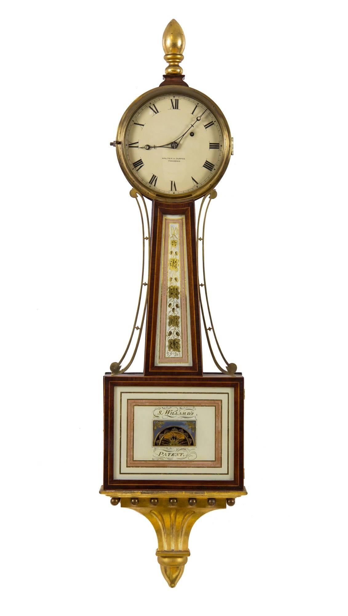 In the world of American banjo clocks, Walter Durfee produced the finest reproductions of the famous Willard timepiece. Durfee was a perfectionist and his hand is seen throughout the choice and quality of painting, wood, etc. The gold leafing is of