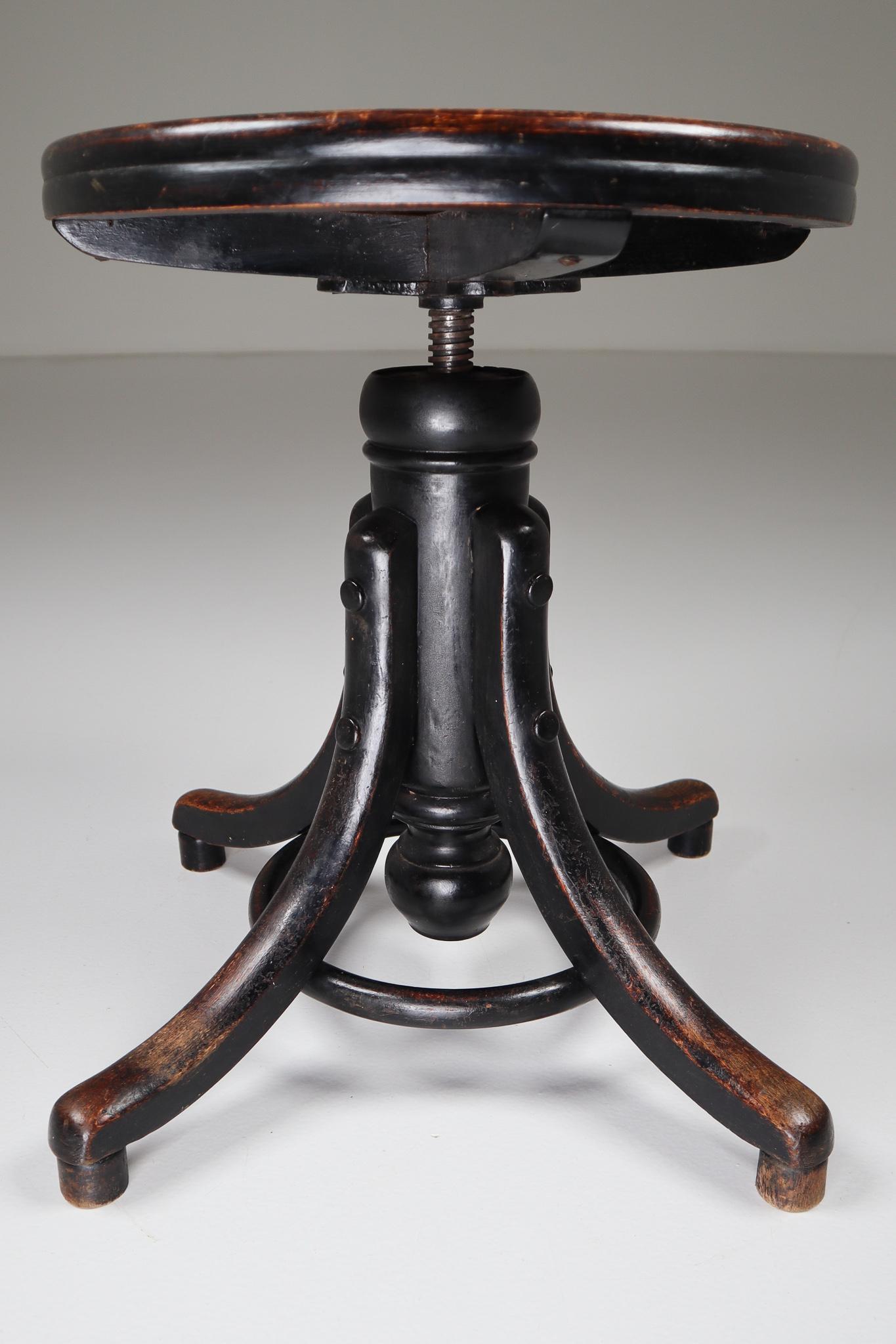Patinated adjustable piano stool by Thonet. Bentwood legs with turned wood vertical standard, and wood disk form seat. Seat spins to adjust height (Total H in upper position 66 inch x 44 cm lower position). Originally designed as piano stool, this