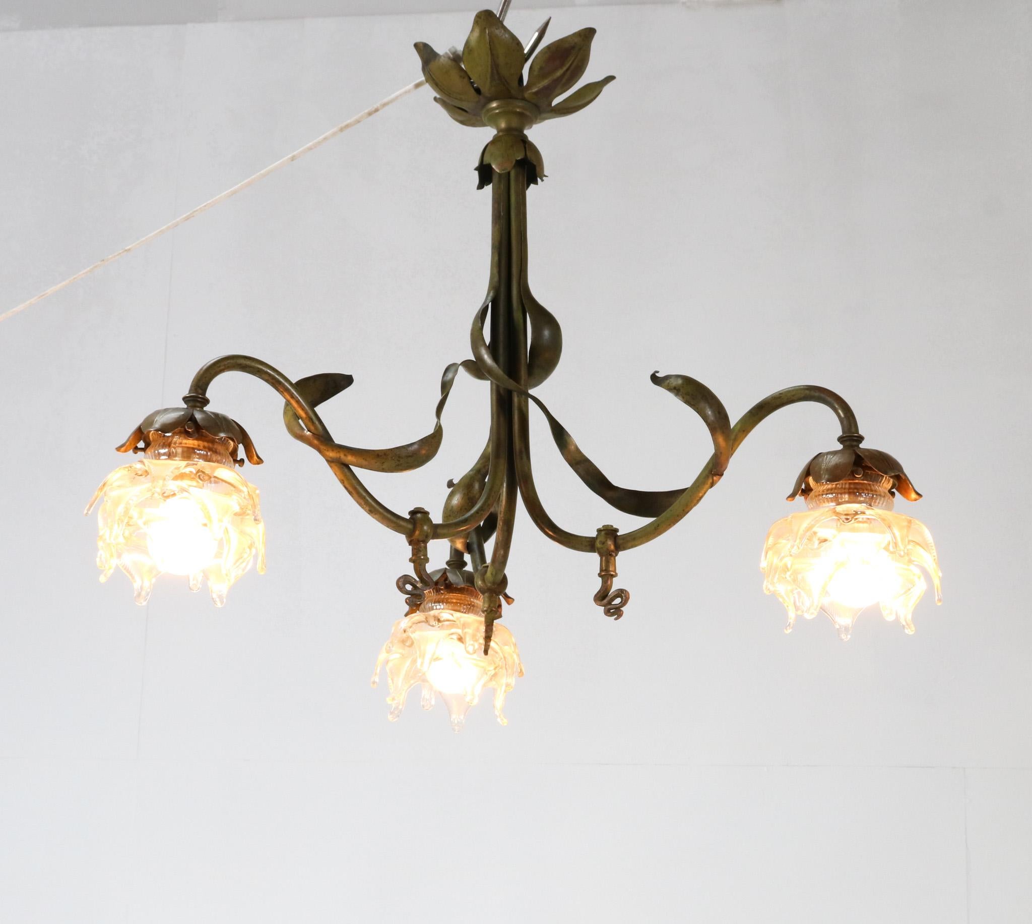 Stunning and rare Art Nouveau three-light chandelier.
Striking French design from the 1900s.
Original patinated brass frame with three original blown glass shades.
This wonderful Art Nouveau three-light chandelier used to be a gas light