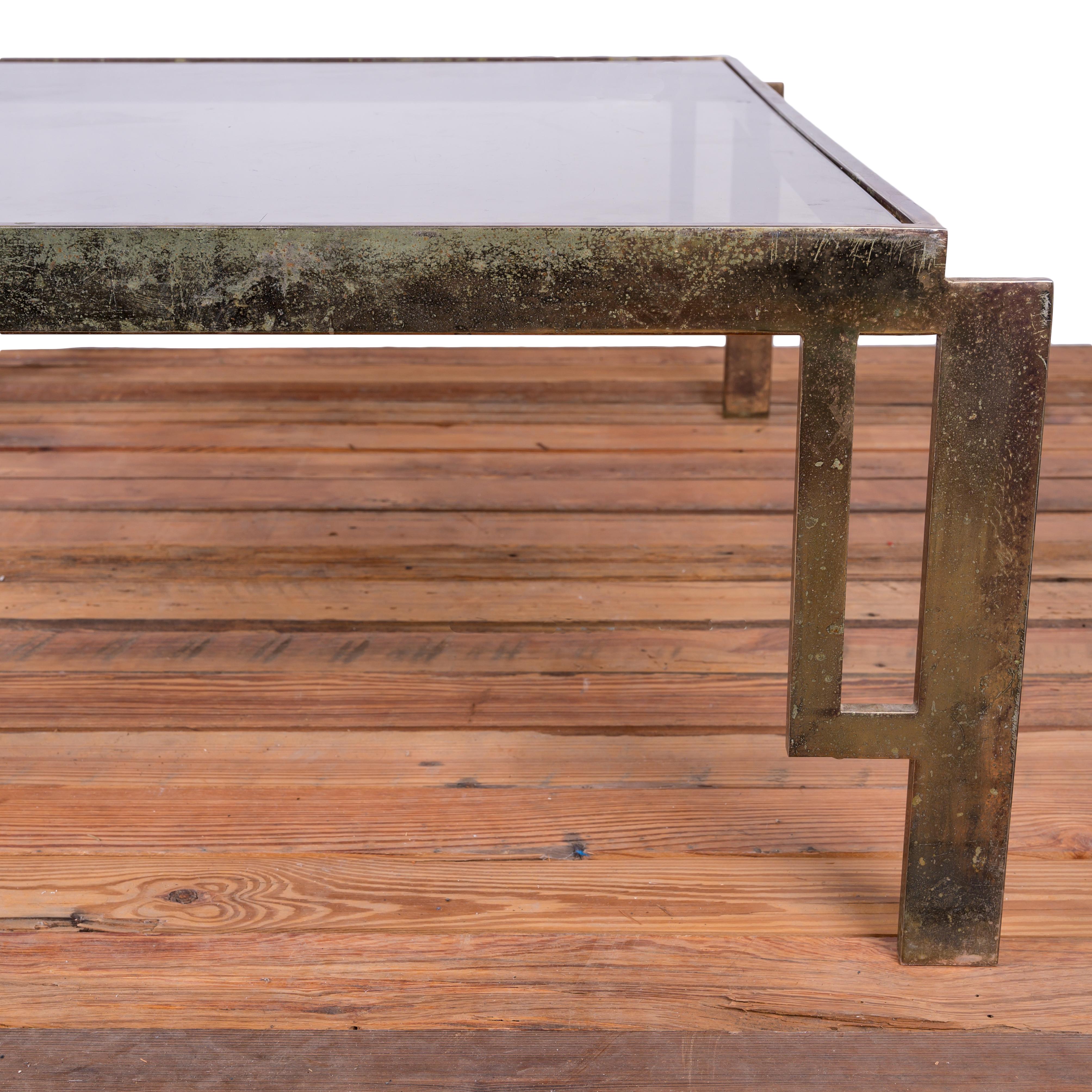 A brass and smoke glass cocktail table made in the 1970s.  It takes years of hard partying to get a perfect patina like this.  

40 inches wide by 40 inches deep by 15 inches tall

