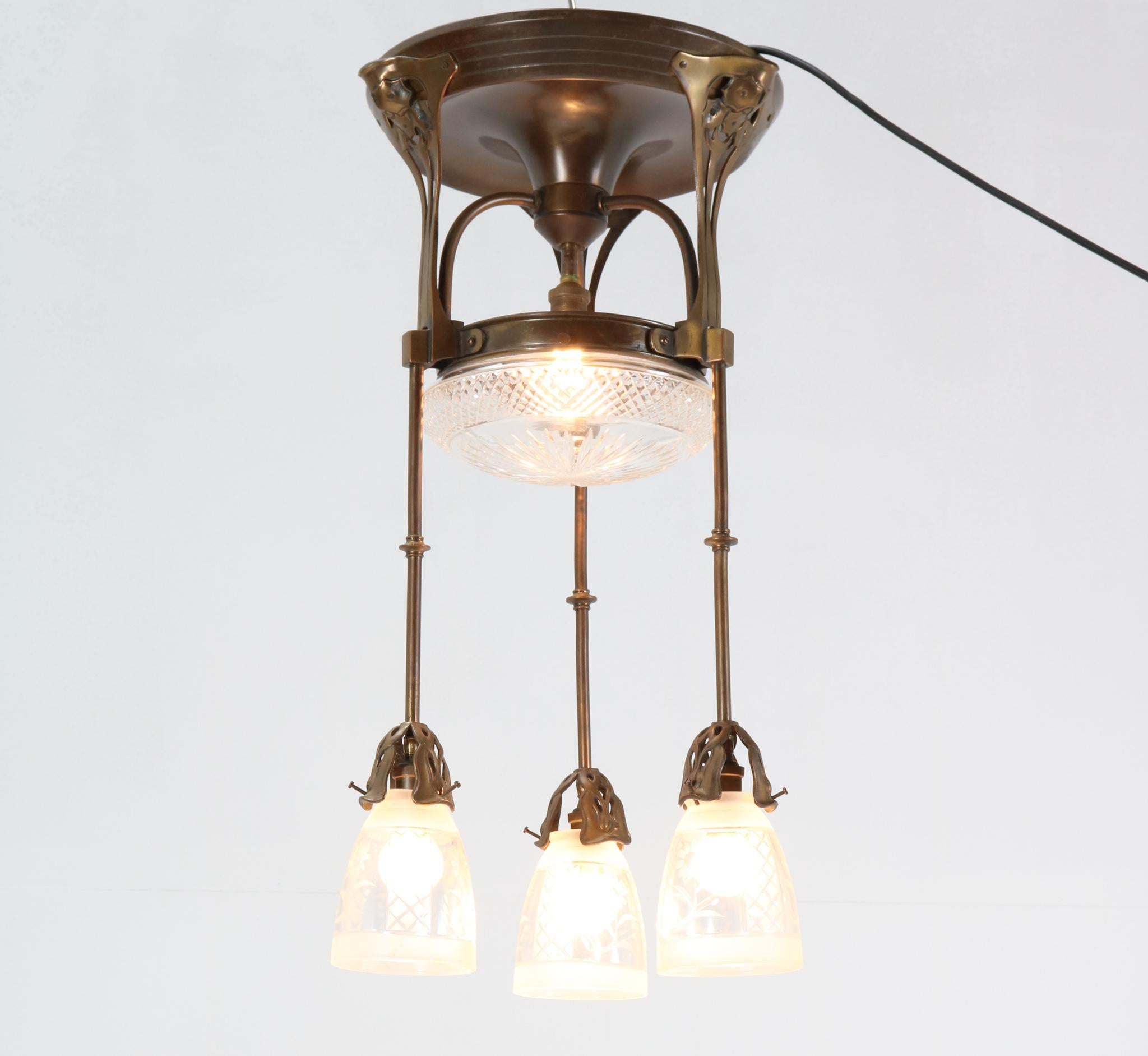 Stunning and rare Jugendstil Art Nouveau chandelier.
Striking German design from the 1900s.
Patinated brass frame with four original hand-blown etched glass shades.
Rewired with four sockets for four B-15 light bulbs.
This wonderful Jugenstil