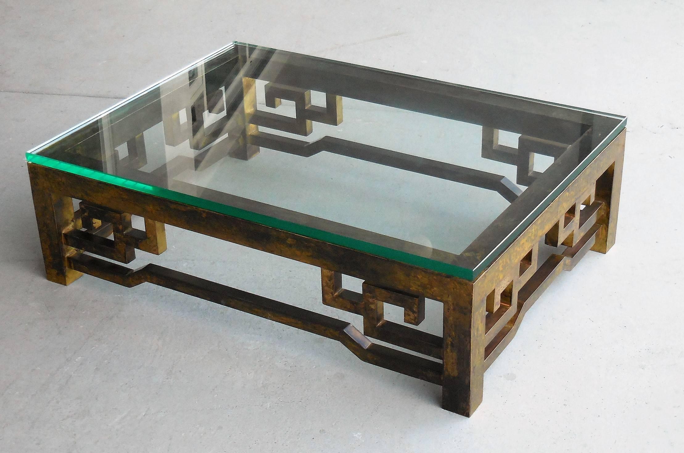 A low brass coffee table with thick glass top. Very beautiful patina on this table.