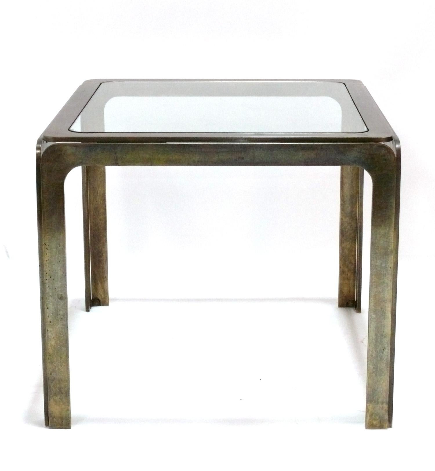 Table d'appoint ou de chevet curviligne en laiton ou bronze patiné, américaine, vers les années 1960. Cette pièce est de taille polyvalente et peut être utilisée comme table d'appoint ou d'appoint, ou encore comme table de nuit. Il est constitué