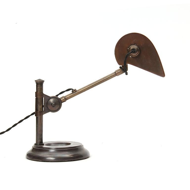 An Industrial patinated brass banker's desk lamp with a pivoting, height-adjustable arm. Made in the USA, circa 1920s.