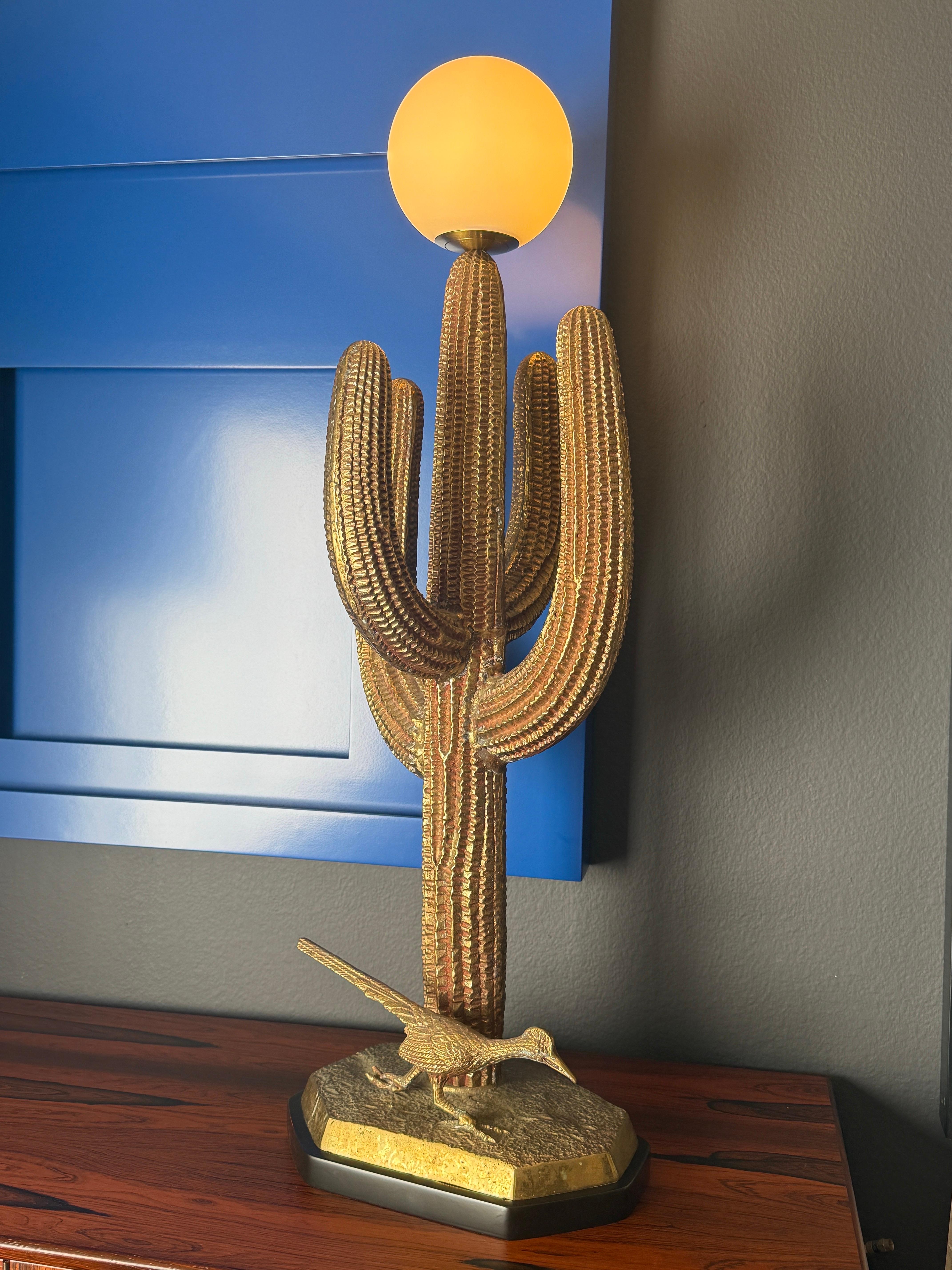 Lámpara escultura de cactus saguaro de latón fundido pesado patinado, montada sobre base de madera negra.
El globo tiene un diámetro de 15 cm y requiere una bombilla LED con base de candelabro de hasta 60 vatios.