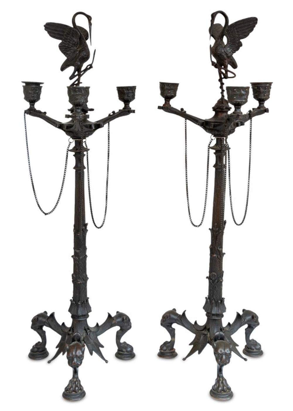 Pair of Patinated Bronze Three Branch Candelabra, after the antique, 19th century, each surmounted by a heron standing on a tortoise, entwined with a snake, below three projecting branches suspended with chains, on a tapering leaf capped column, on