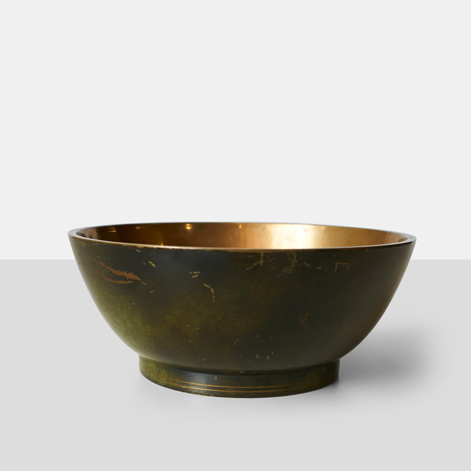 A patinated bronze bowl with highly polished interior. The rim of the foot has a relief pattern of concentric stripes. Designed and manufactured by Krone Bronce in Denmark. Stamped with the makers mark on the base.