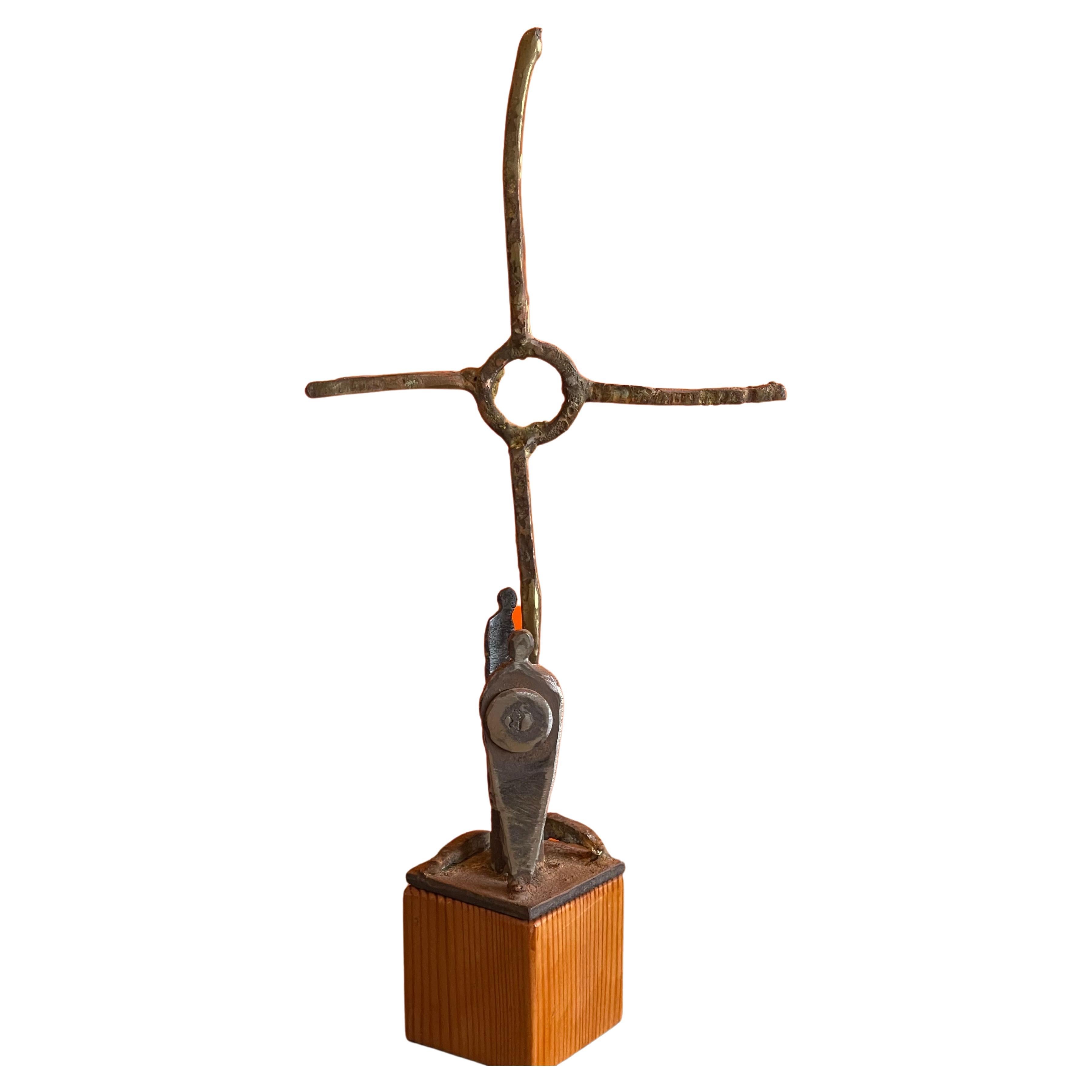 Patinated bronze cross sculpture on wood base by listed artist Greg Bressani, circa 2018. The piece has a wonderful patina and measures 7
