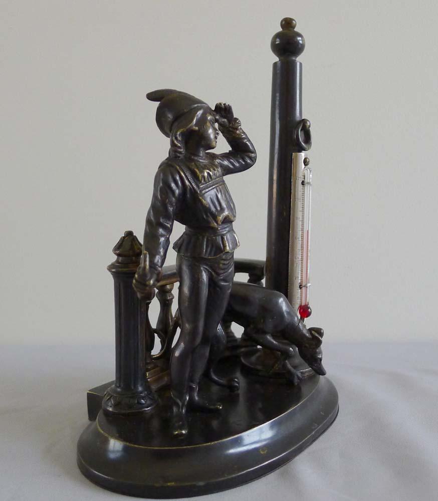 Antique patinated bronze figural thermometer of a medieval youth and his hound.
Probably English this is an unusual desk thermometer with a hunting theme.
Set on an oval base the standing figure of a hunter looks into the middle distance for his