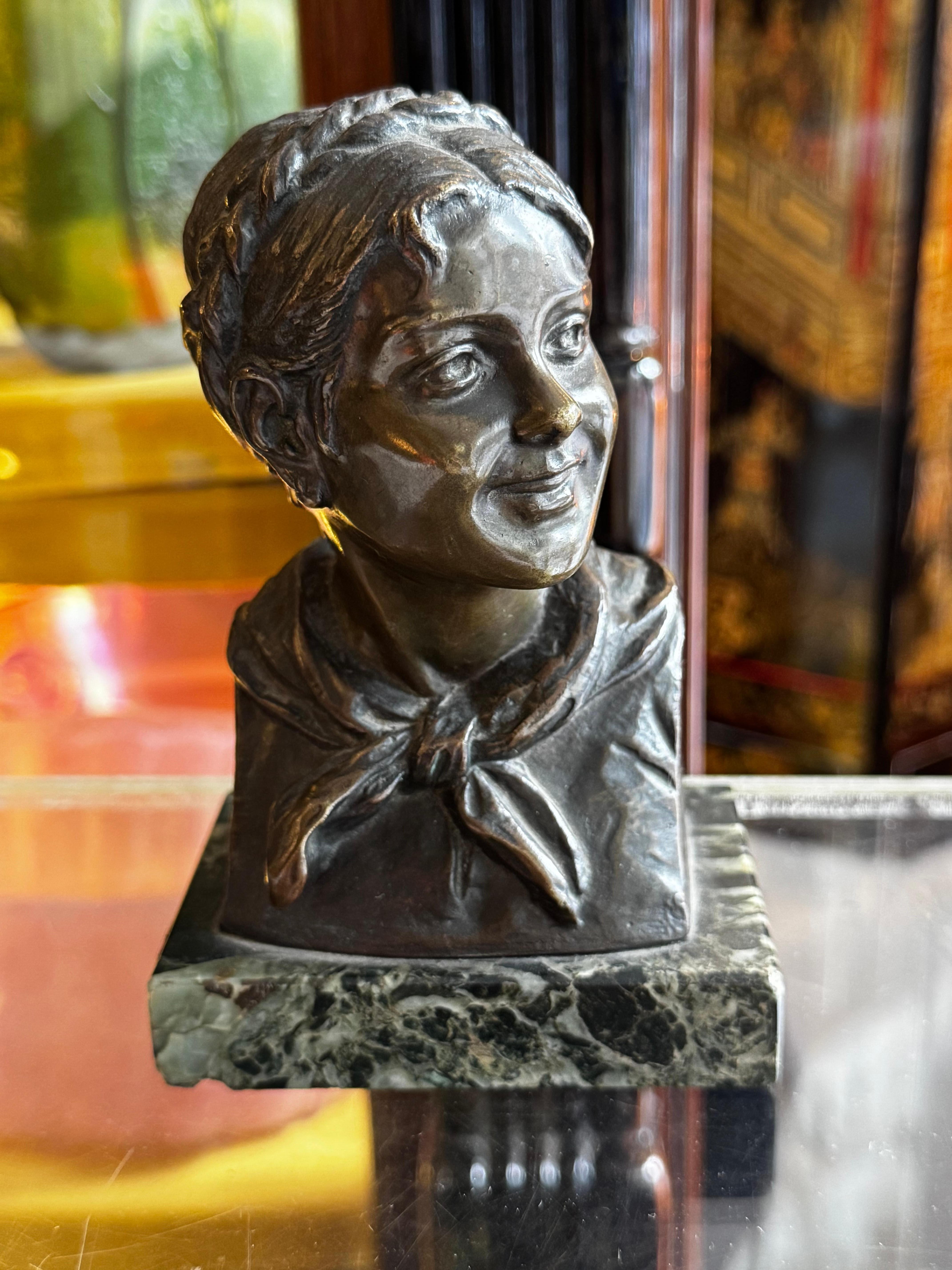 Questa splendida scultura di busto di ragazza, realizzata in bronzo patinato, è una vera e propria testimonianza della maestria e dell'abilità del rinomato scultore Dimanche. Firmato dall'artista, questo pezzo cattura magnificamente i tratti