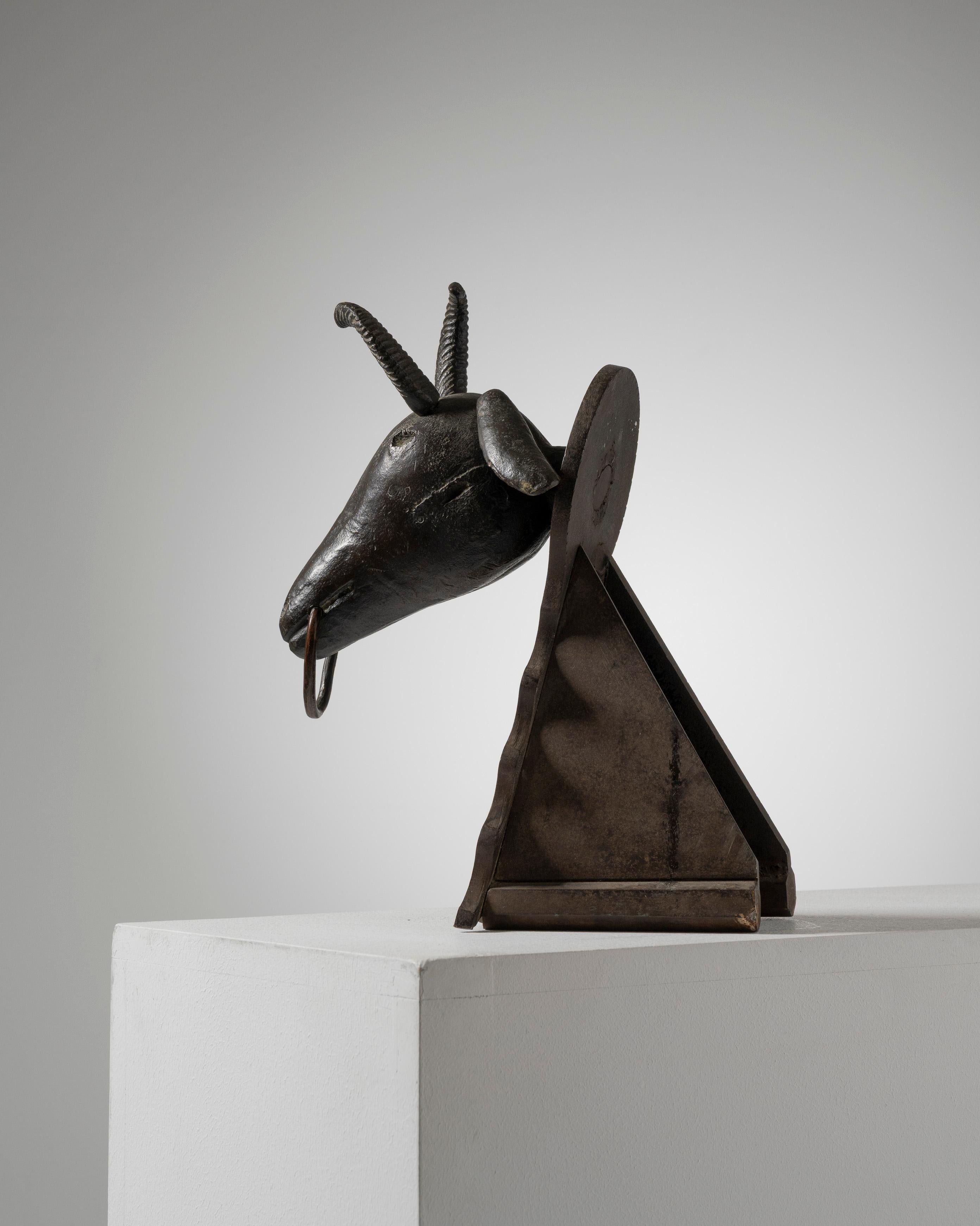 Scultura in bronzo patinato di una testa di capra con anello, anni '20.
Questa scultura in bronzo patinato marrone raffigura una testa di capra ornata da un anello che attraversa il muso. Creato negli anni '20, poggia su una base triangolare che