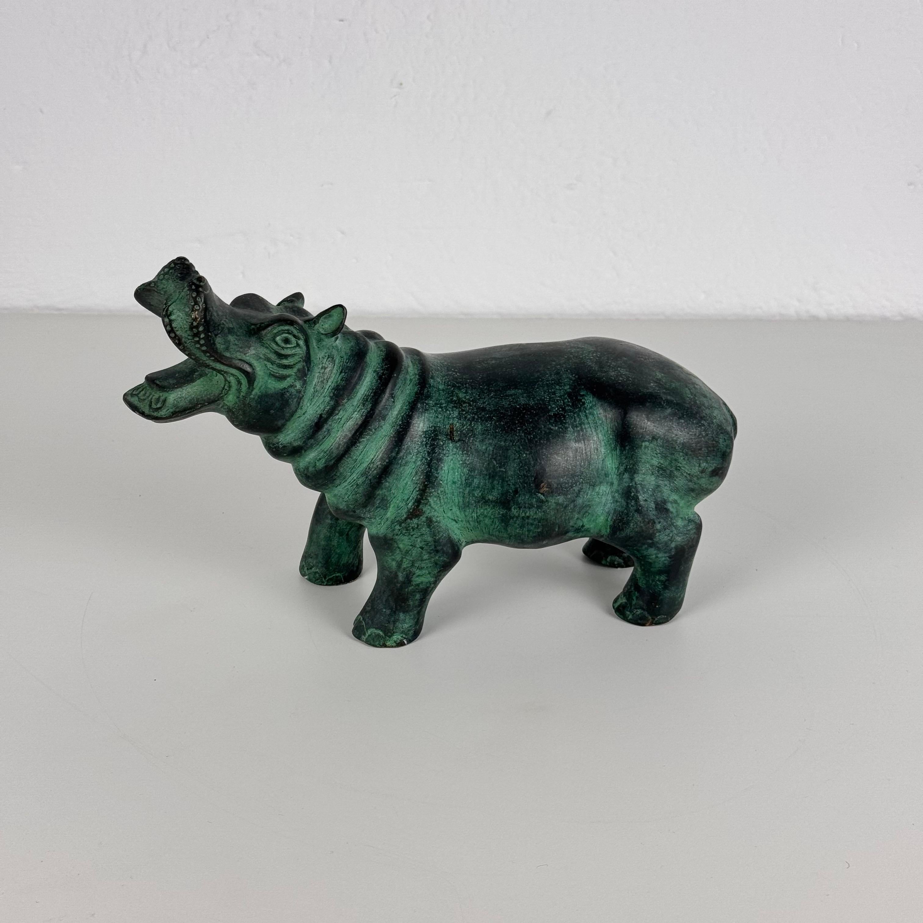 A striking patinated bronze hippopotamus sculpture from the 1980s, featuring a beautifully aged surface that enhances its sculptural presence. The piece captures the essence of this majestic animal with remarkable detail and weight, making it a