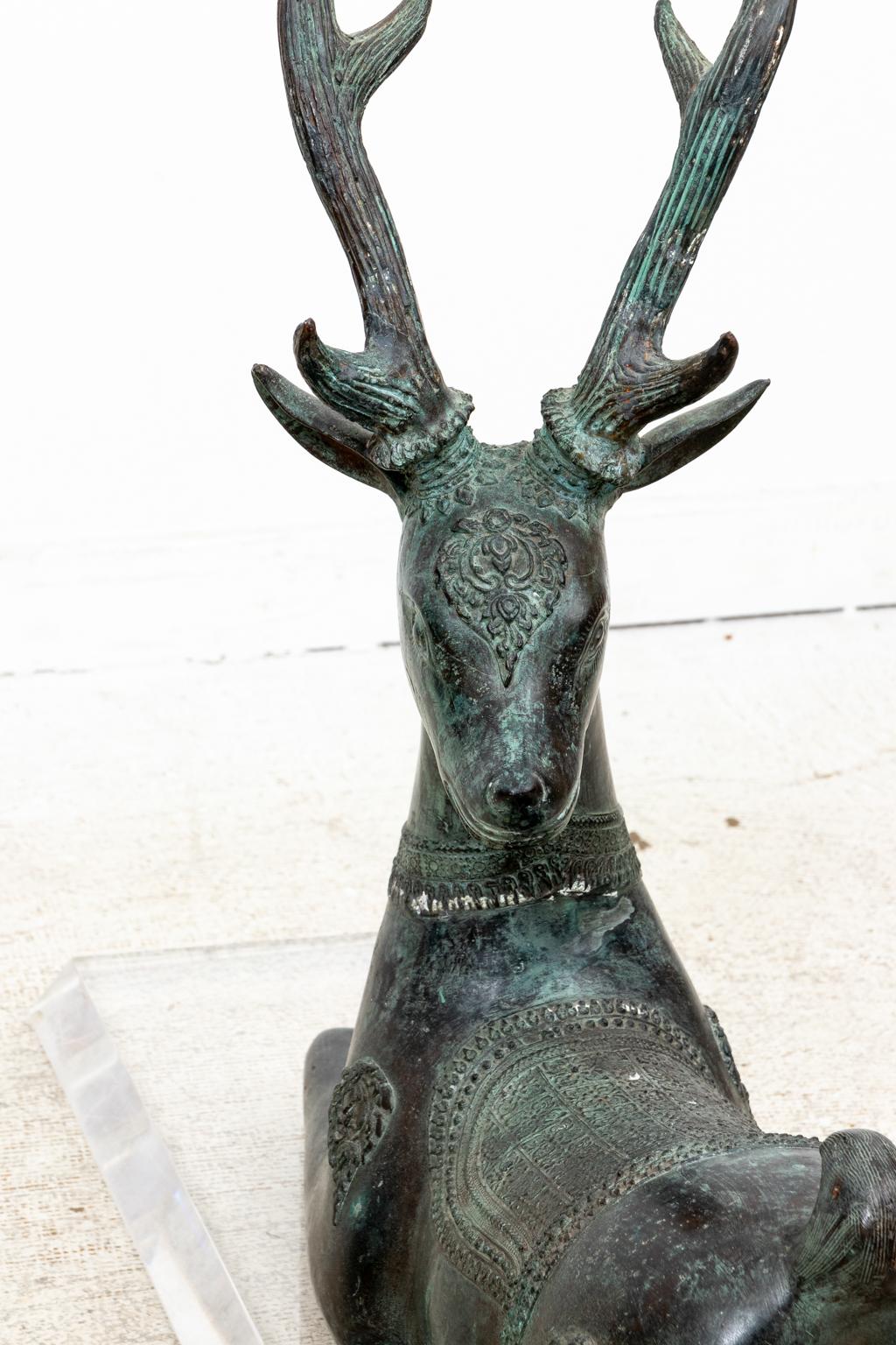 Circa mid-20th century detailed patinated bronze reclining deer sculpture on lucite base with high quality construction in the style of Sarried or The Rudolph Collection. Very good vintage condition with slight scratching on lucite base consistent