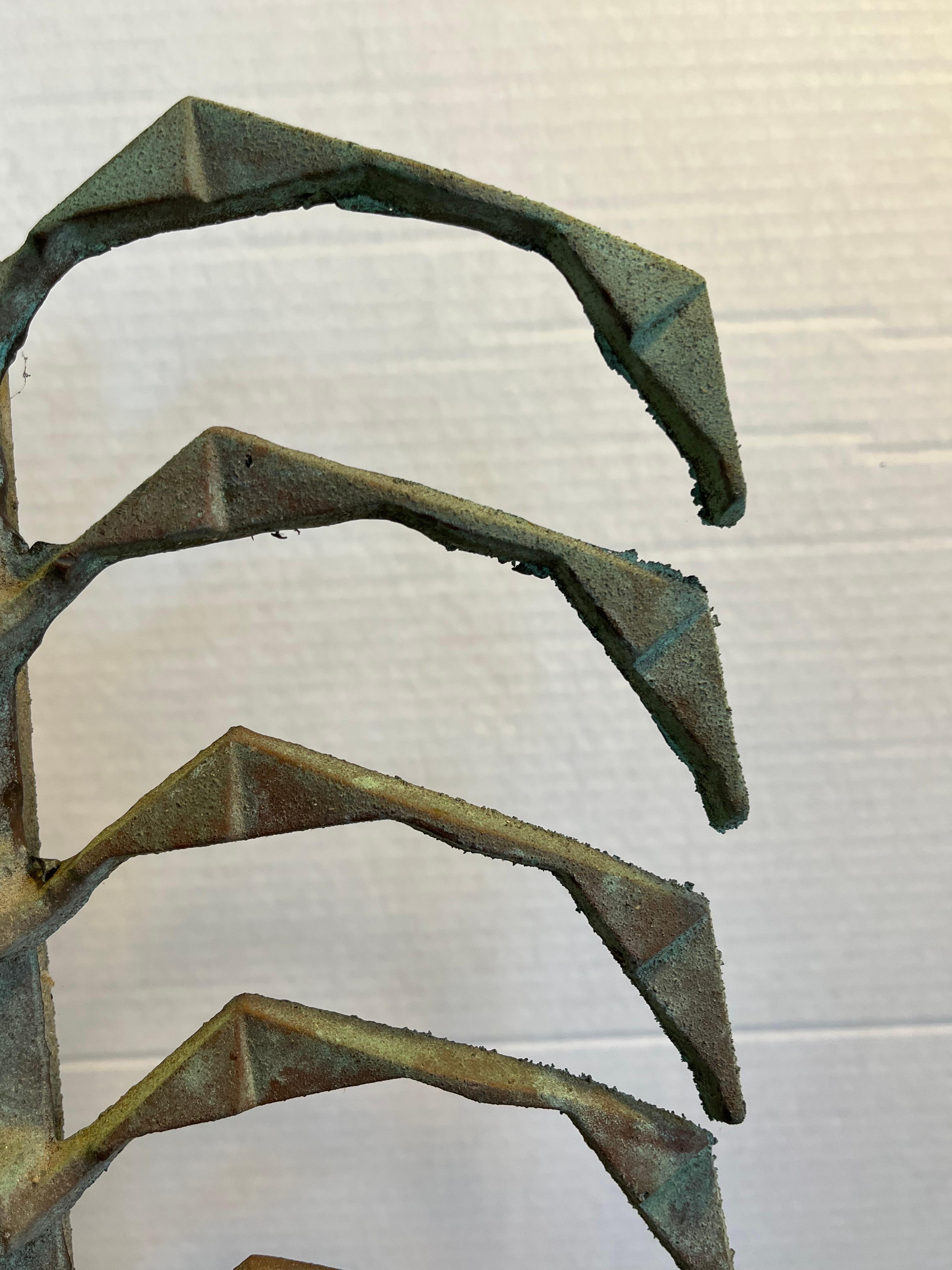This cast patinated sculpture can be hung by the ring at the top or stand upright on a flat surface. It also bears the foundry mark of Scoleri. 