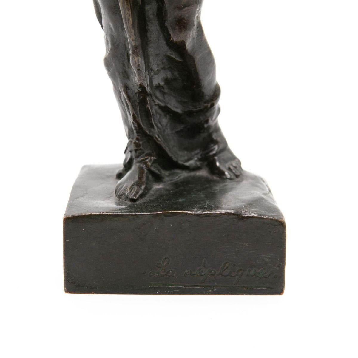 Elegante escultura de bronce patinado que representa a una mujer de pie con una postura tranquila y contemplativa. 
La base lleva inscrito el texto 